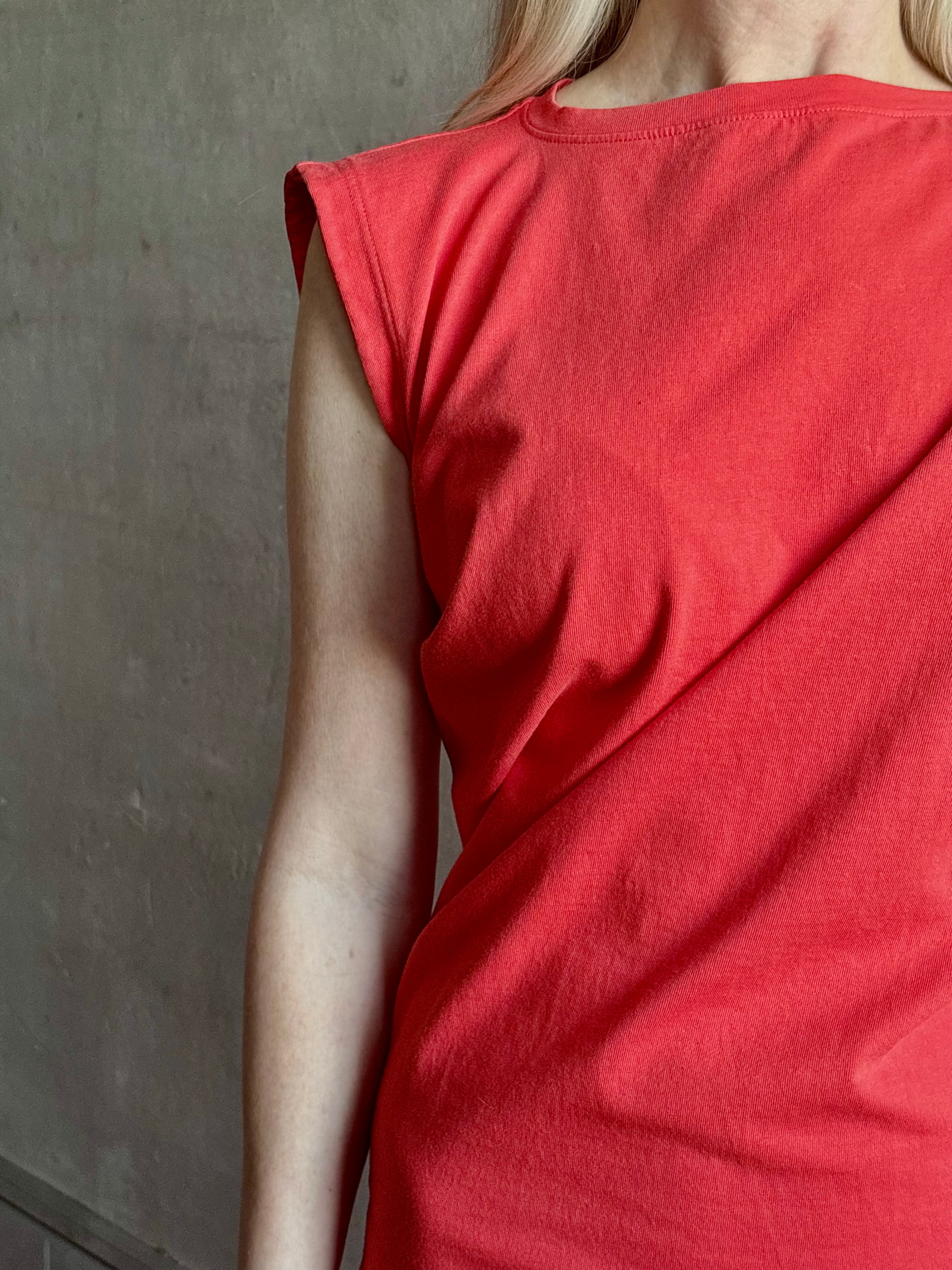 Woman wearing the red Beth Dress from Agolde crafted from 100% cotton with short sleeves, knee length and asymmetrical twist draping in a effortless relaxed fit