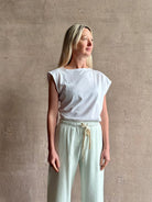 Mature woman wearing a white asymmetrical beth tee shirt from Agolde  with short sleeves, crew neckline and architectural draping