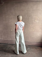 Mature woman wearing a white asymmetrical beth tee shirt from Agolde  with short sleeves, crew neckline and architectural draping