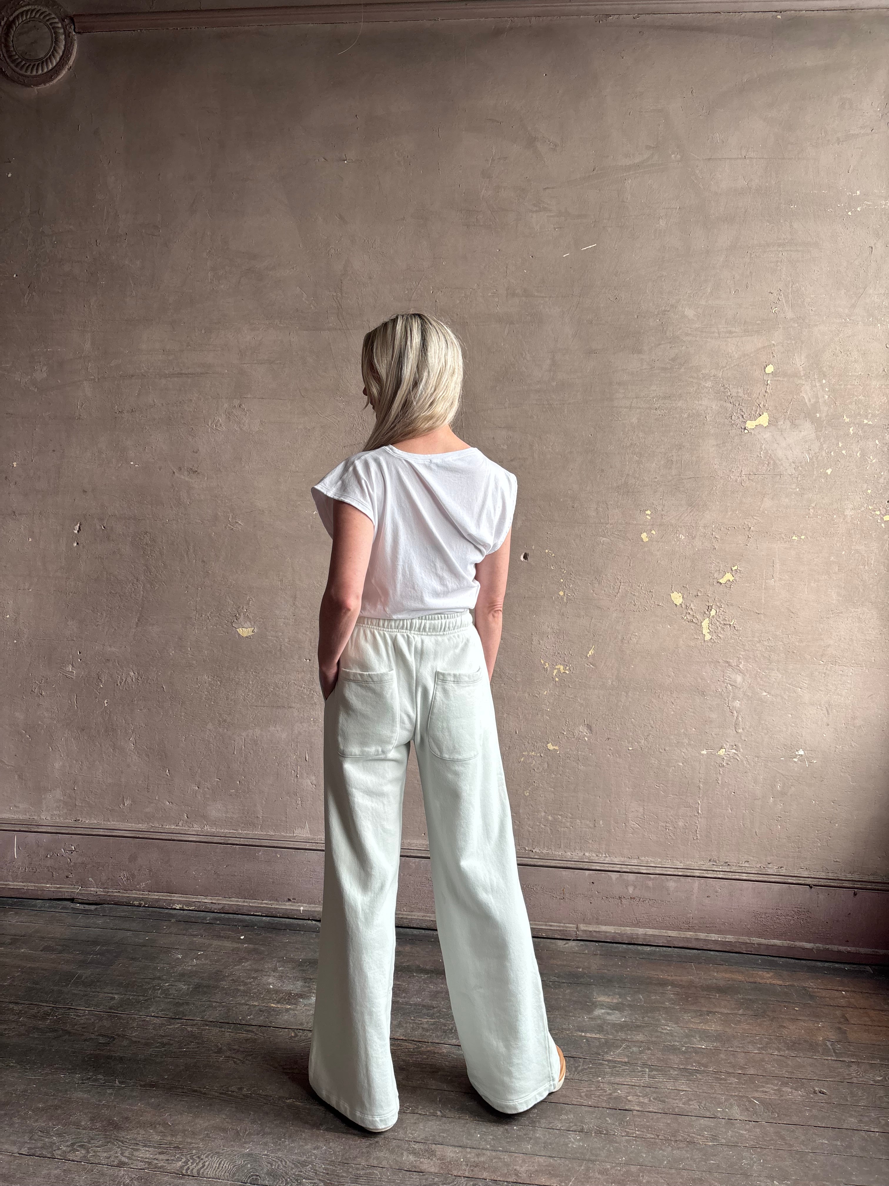 Mature woman wearing a white asymmetrical beth tee shirt from Agolde  with short sleeves, crew neckline and architectural draping