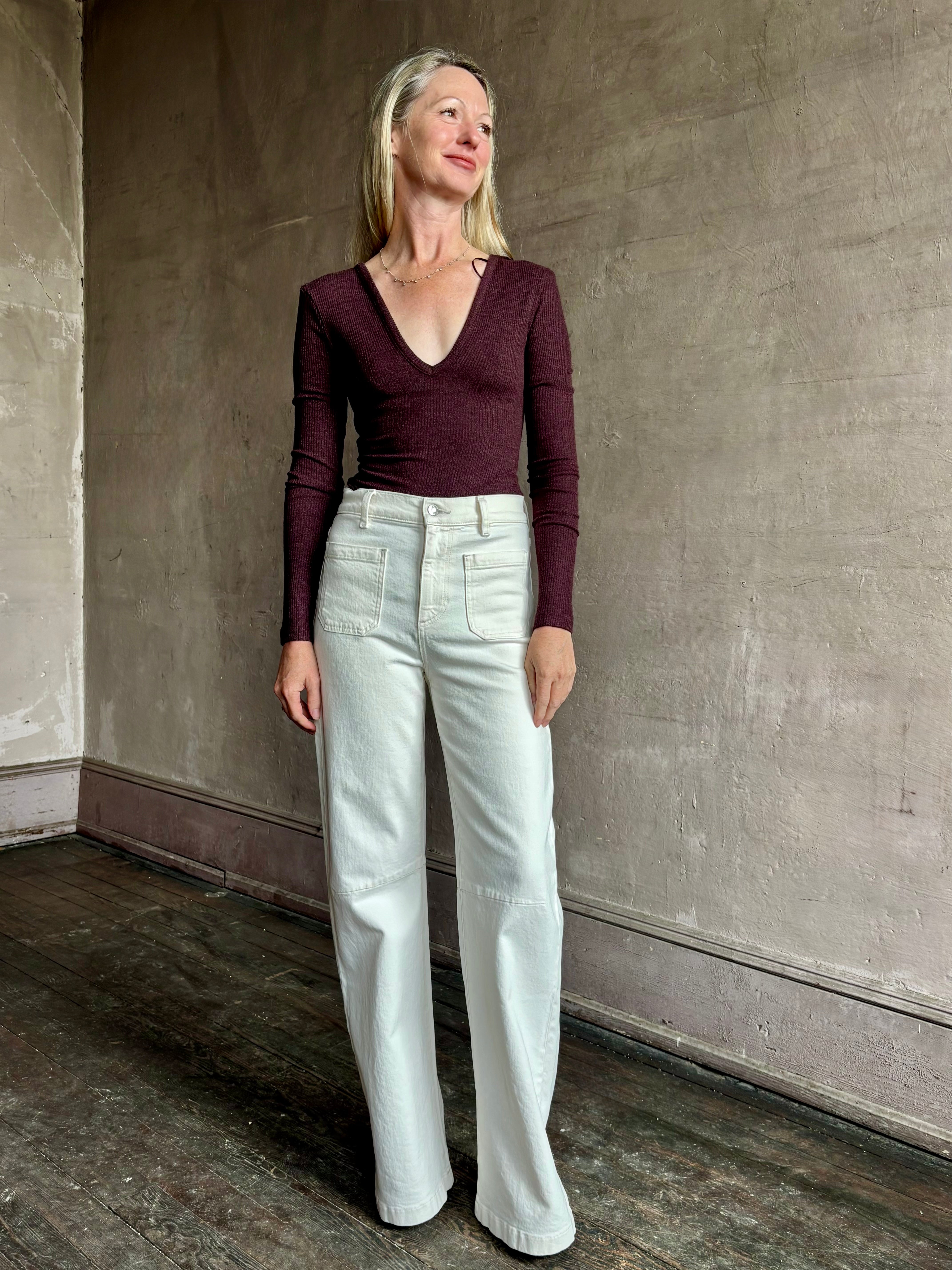 Image of woman wearing Agolde Darla Bodysuit in raisin colorway with deep v-neck and long sleeves perfect for layering