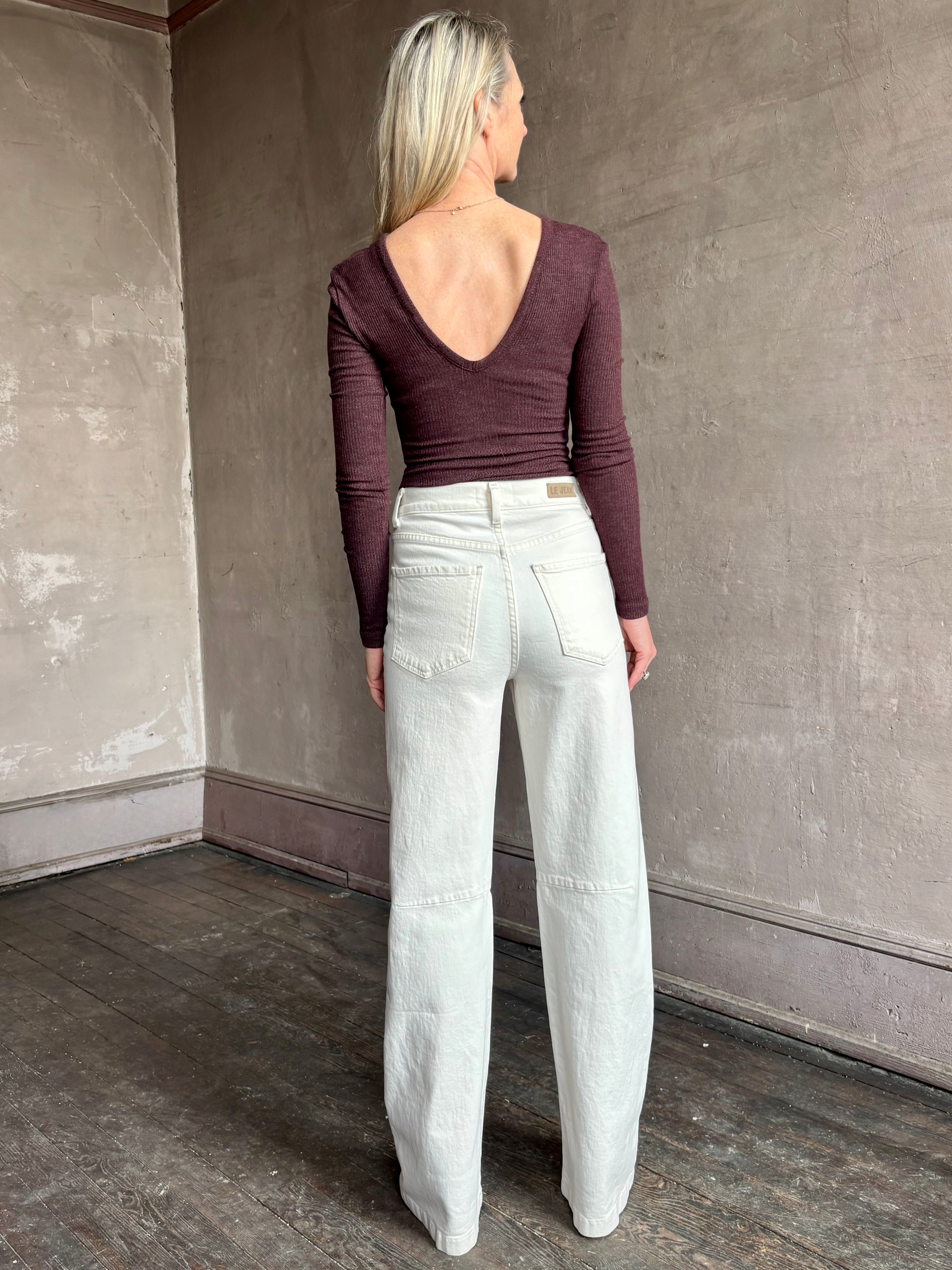 Image of woman wearing Agolde Darla Bodysuit in raisin colorway with deep v back and long sleeves perfect for layering