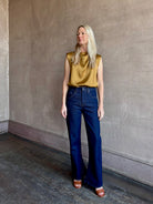 Image of mature woman wearing premium LA regenerative denim AGOLDE Kick Boot Ankle in Reissue dark wash with no distressing and a finished hem