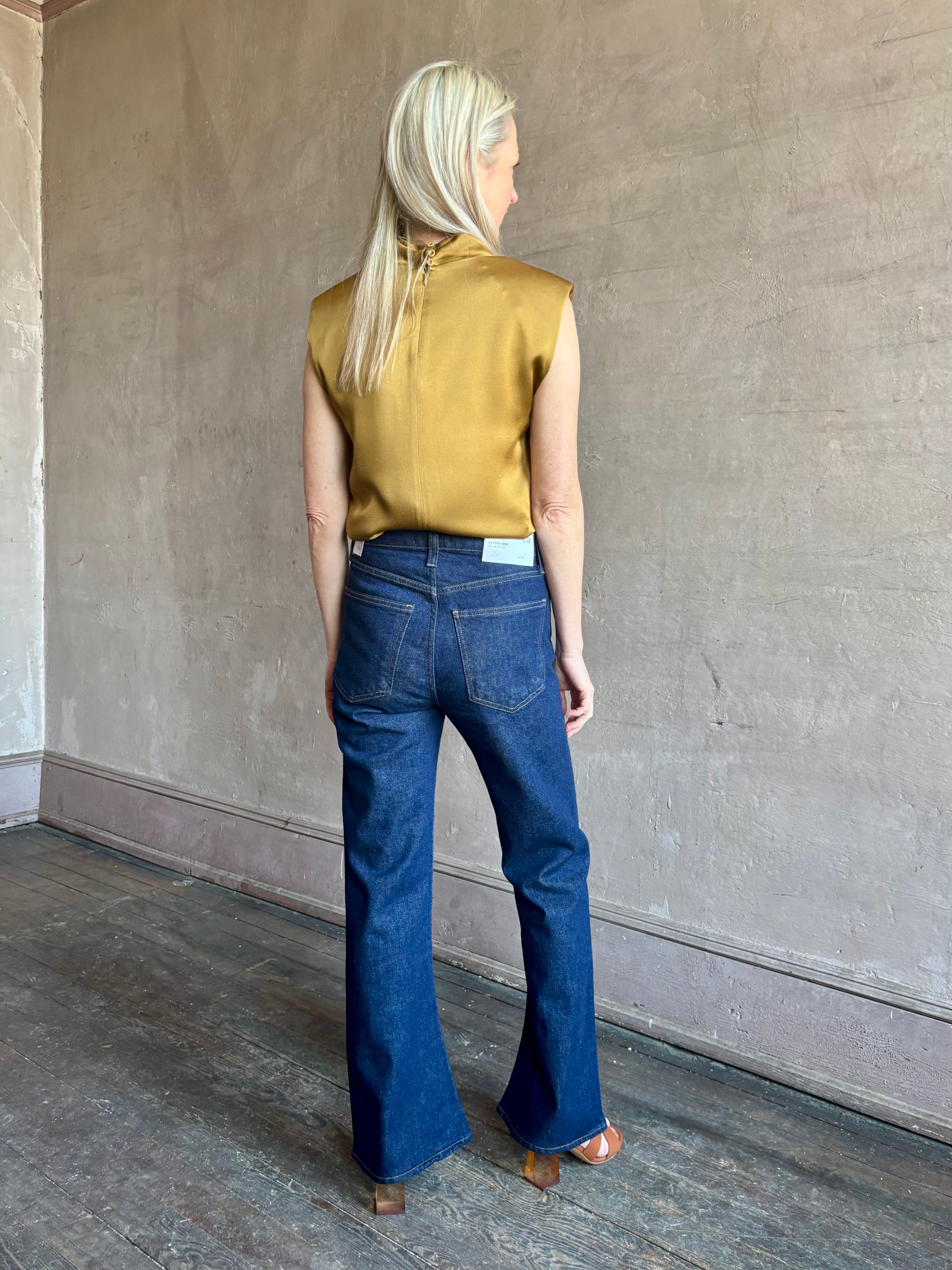 Image of mature woman wearing premium LA regenerative denim AGOLDE Kick Boot Ankle in Reissue dark wash with no distressing and a finished hem