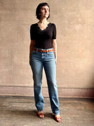 Woman wearing low rise slim denim from Agolde in Kindle medium wash with straight leg and finished hem line