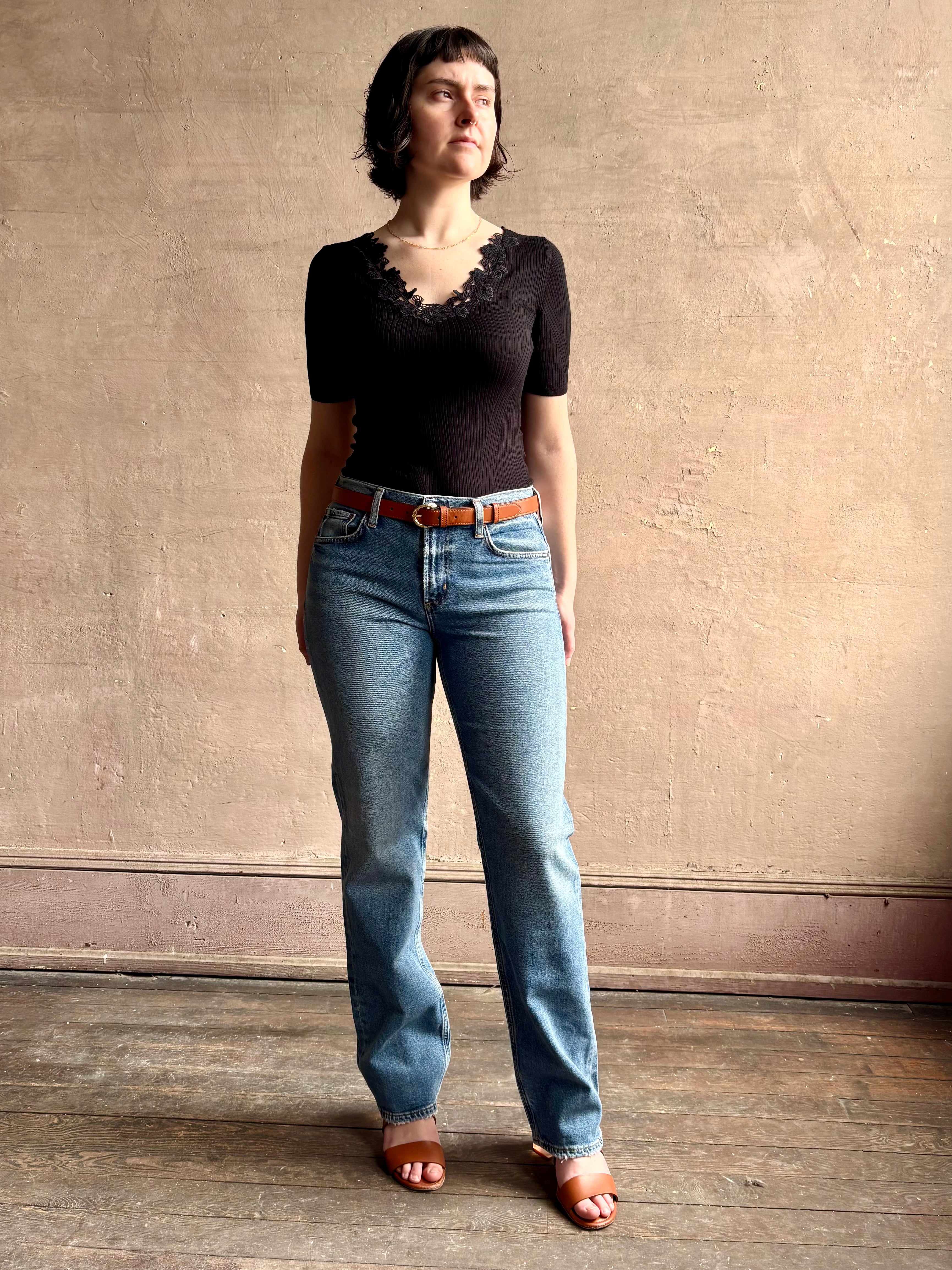 Woman wearing low rise slim denim from Agolde in Kindle medium wash with straight leg and finished hem line