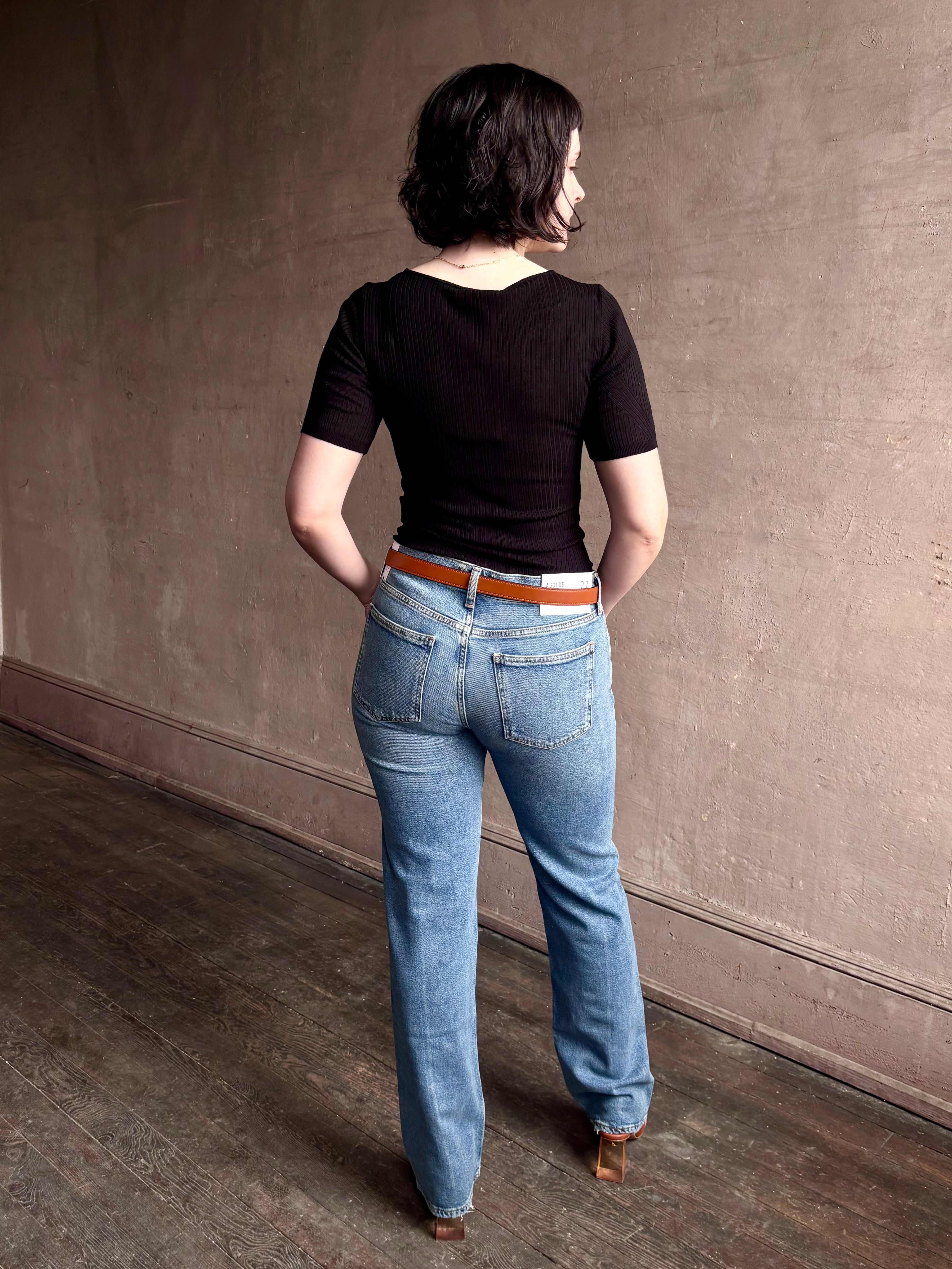 Woman wearing low rise slim denim from Agolde in Kindle medium wash with straight leg and finished hem line