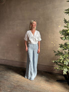 Mature woman wearing The A.L.C. Jordan Top in White Long sleeve blouse boasts premium cotton blend with v-neck and tab to roll sleeves up to a half sleeve