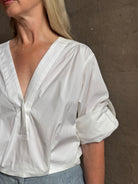 Mature woman wearing The A.L.C. Jordan Top in White Long sleeve blouse boasts premium cotton blend with v-neck and tab to roll sleeves up to a half sleeve