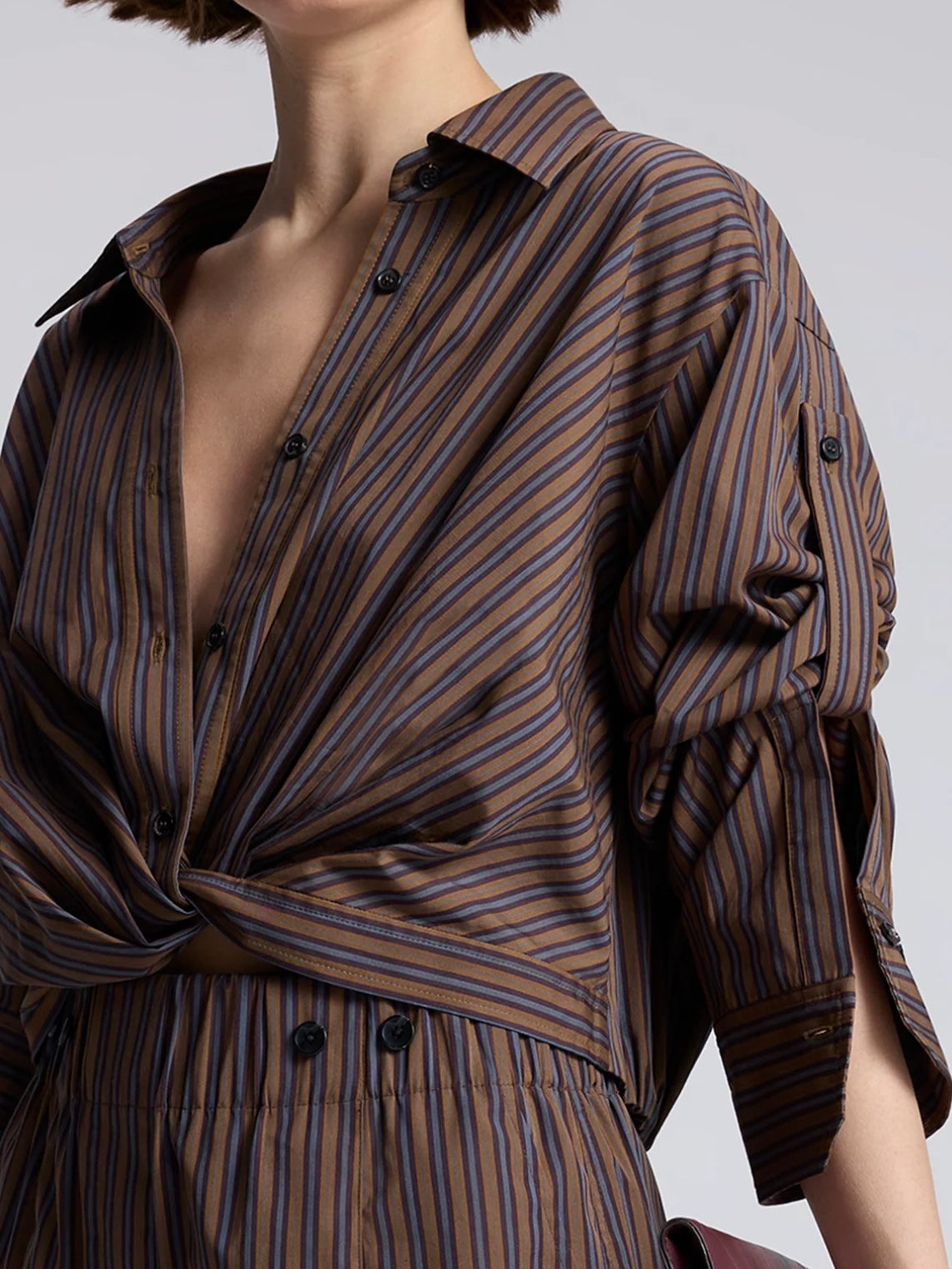 Model wearing the cotton ALC Leo button down shirt with brown and blue stripes and crop twist front
