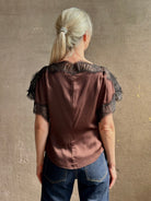 Image of mature woman wearing ALC Luna top in premium chocolate brown viscose blouse with a boat neck short sleeve and refined black lace trim