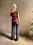 Mature woman wearing A.L.C.'s Nara Top in burgundy cotton poplin cold shoulder draping feminine cosmopolitan tailoring