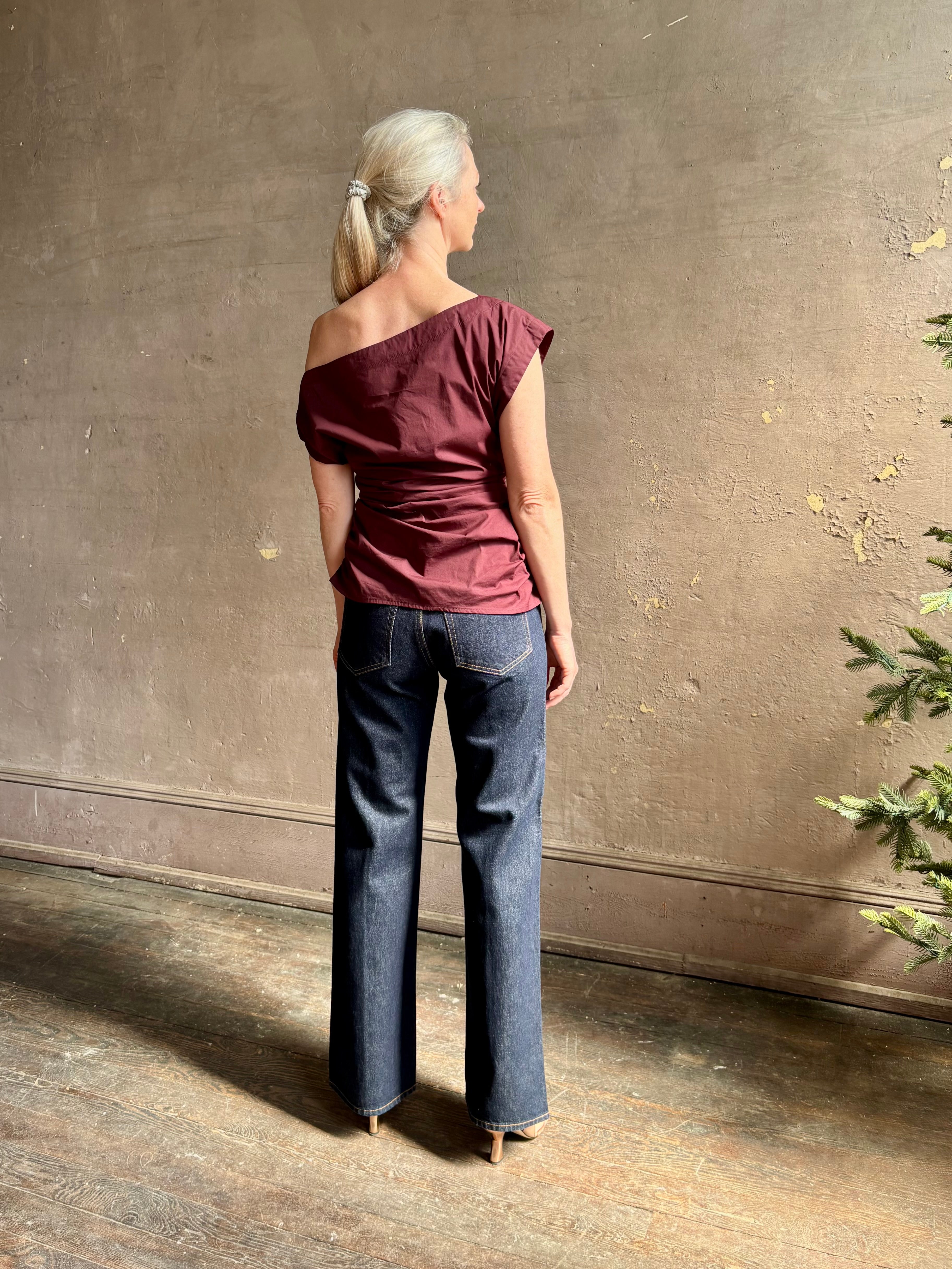 Mature woman wearing A.L.C.'s Nara Top in burgundy cotton poplin cold shoulder draping feminine cosmopolitan tailoring
