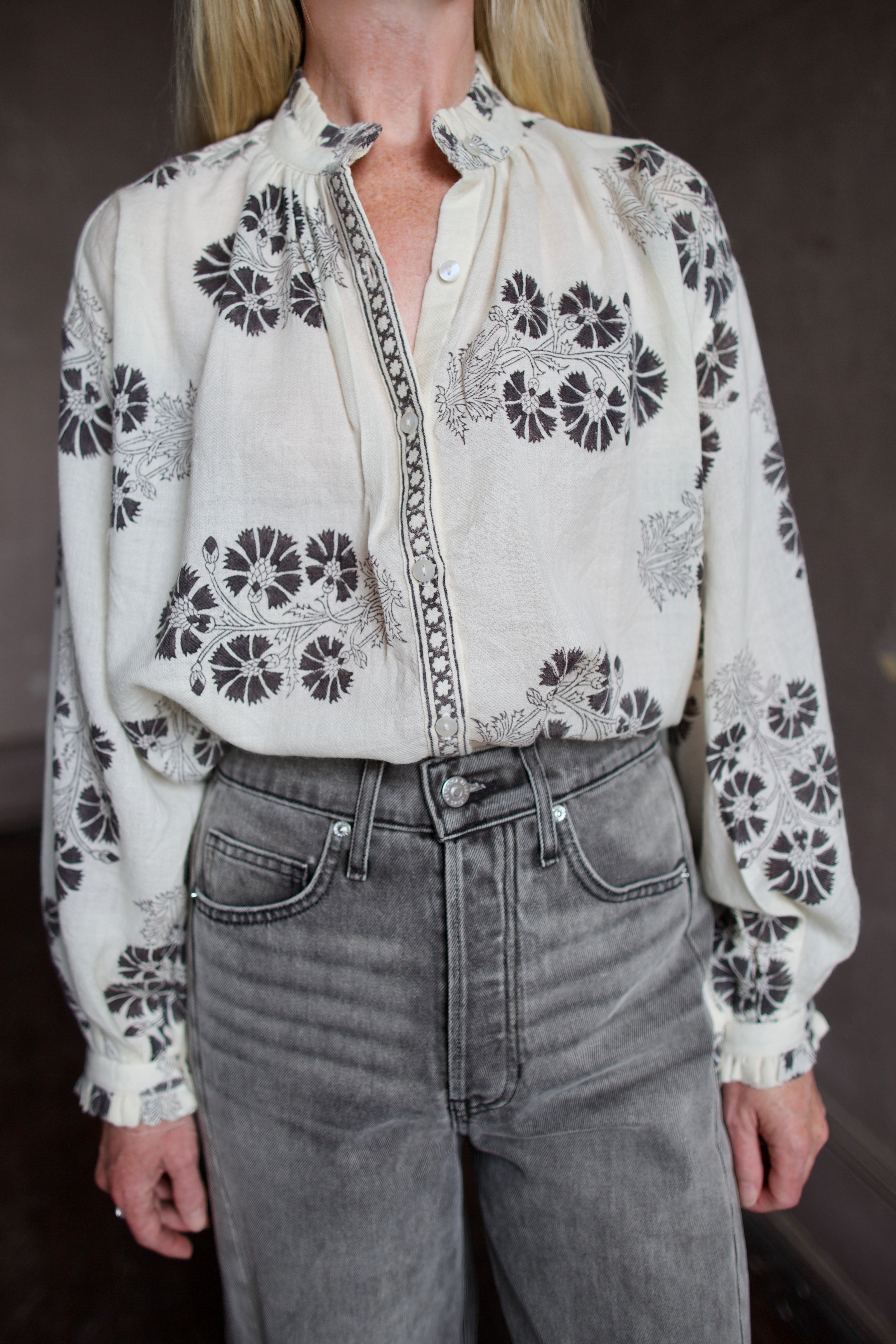 Model wearing an Alix of Bohemia wool floral blouse and Veronica Beard high-waisted grey barrel jeans.