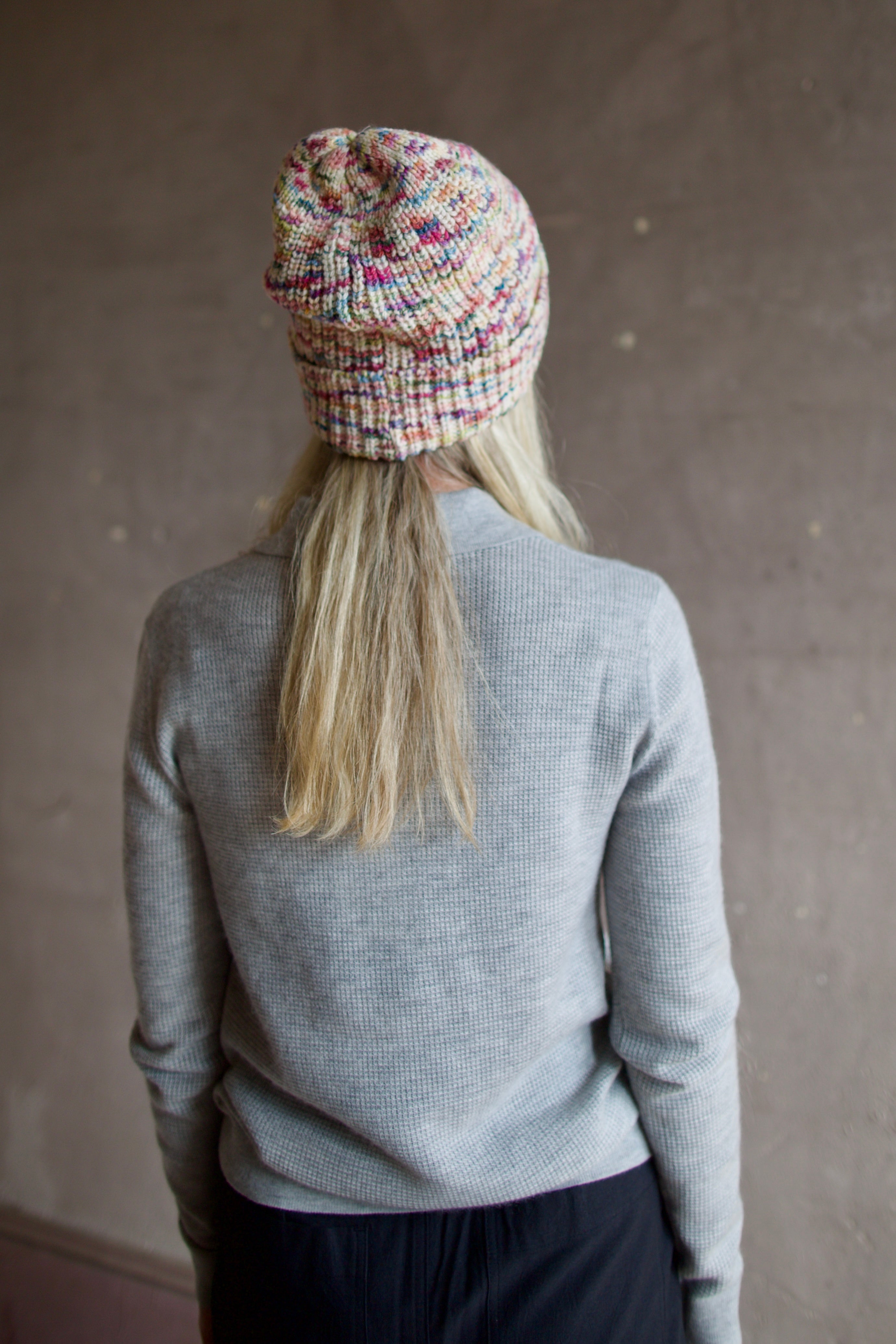Model wearing Alix of Bohemia Yara Aurora Beanie. Knitted beanie is multicolored with cuff detail.  
