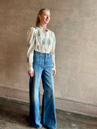 Image of woman wearing ALIX OF BOHEMIA Artemis Sky Mist Flower Shirt with Off-White background and aqua and pink floral print