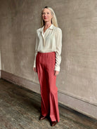 Woman wearing sophisticated ALIX OF BOHEMIA Charlie Red Ochre Silk Pant with belt loops, flat front and full length straight leg