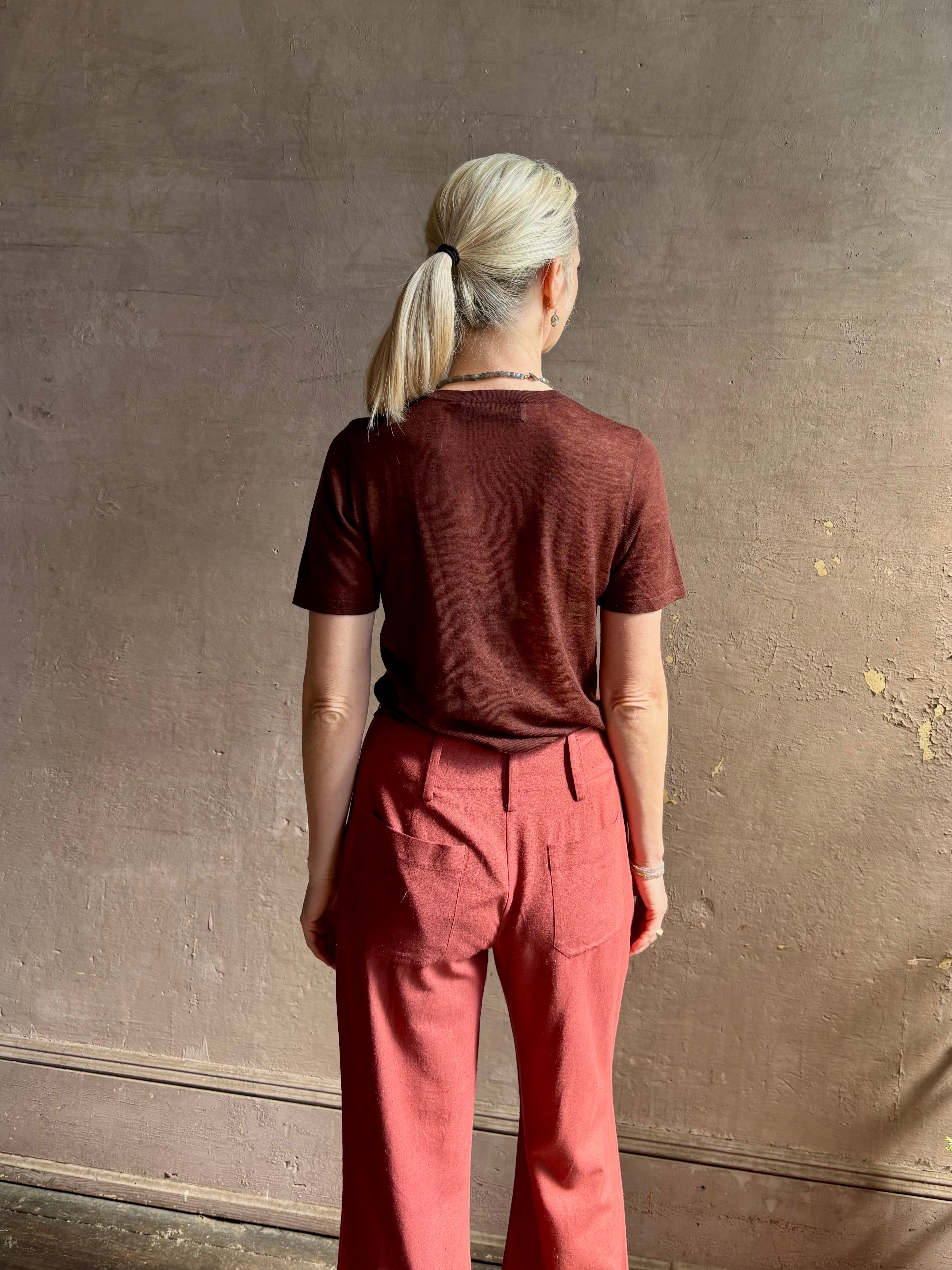 Woman wearing sophisticated ALIX OF BOHEMIA Charlie Red Ochre Silk mid-rise Pant with front and back pockets, belt loops, flat front and full length straight leg