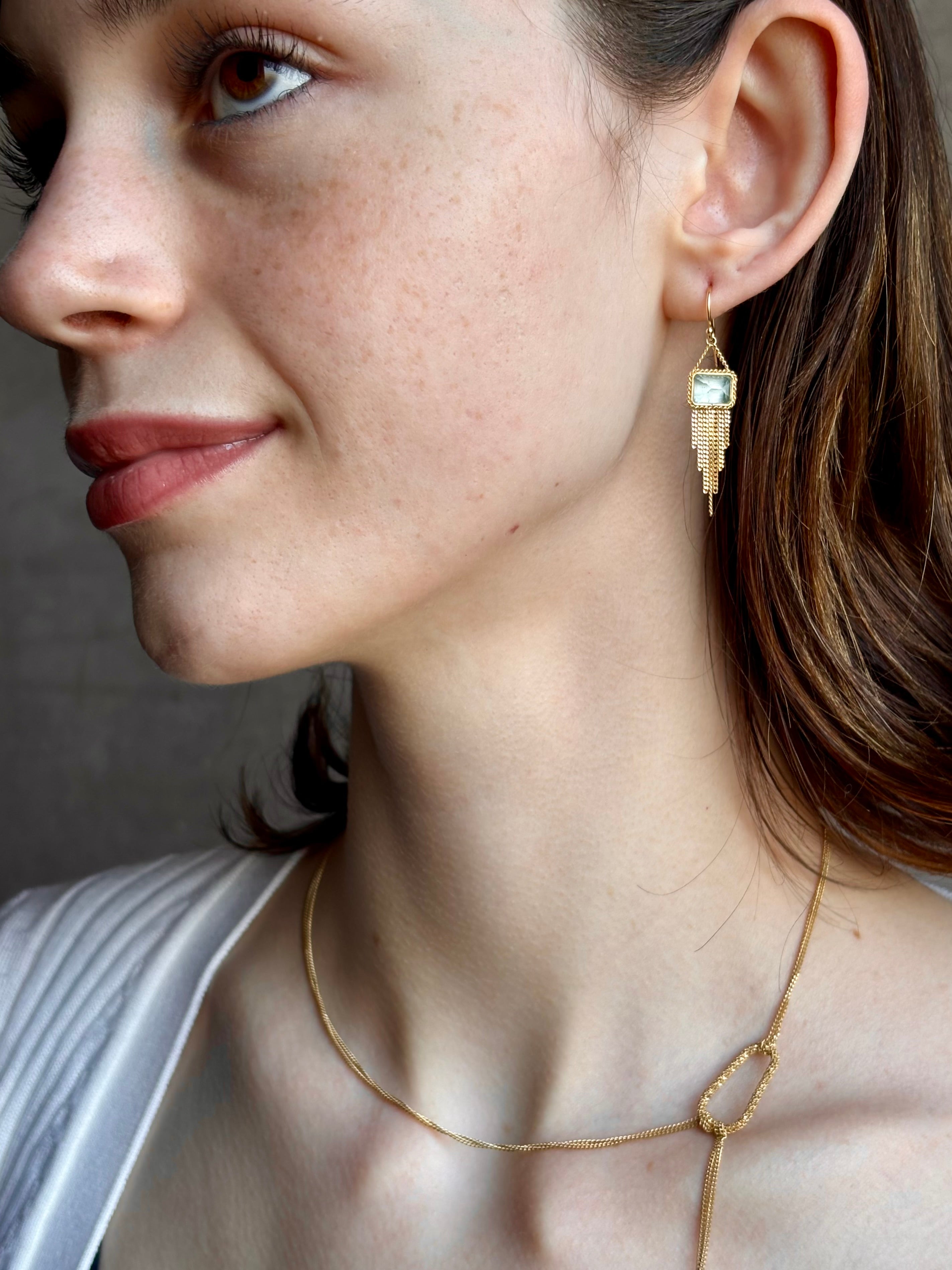 Woman wearing handmade New York designer Amali rectangular aquamarine and 18k yellow gold drop earrings with elegant  gold fringe dangle embellishments