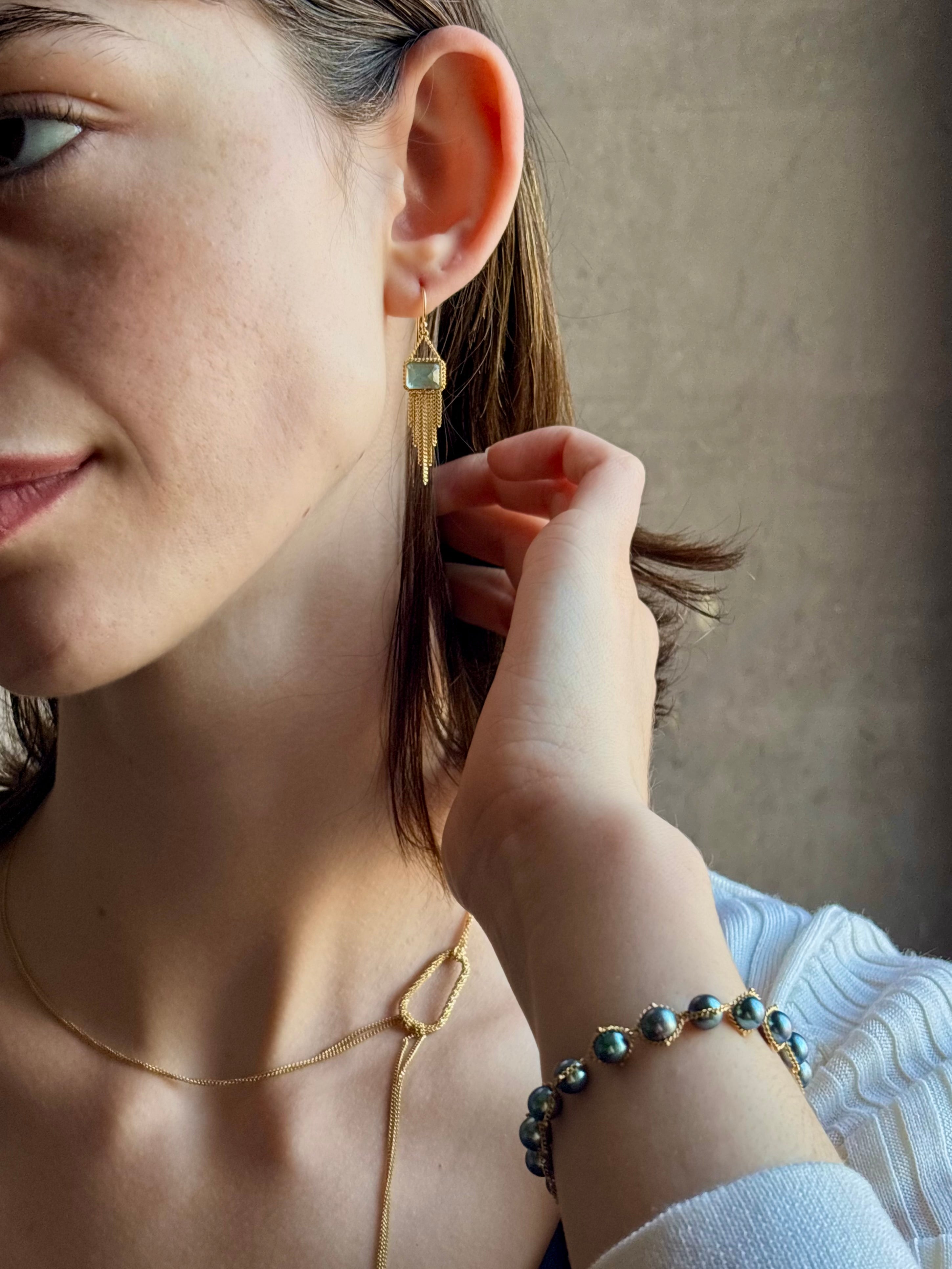 Woman wearing handmade New York designer Amali rectangular aquamarine and 18k yellow gold drop earrings with elegant  gold fringe dangle embellishments