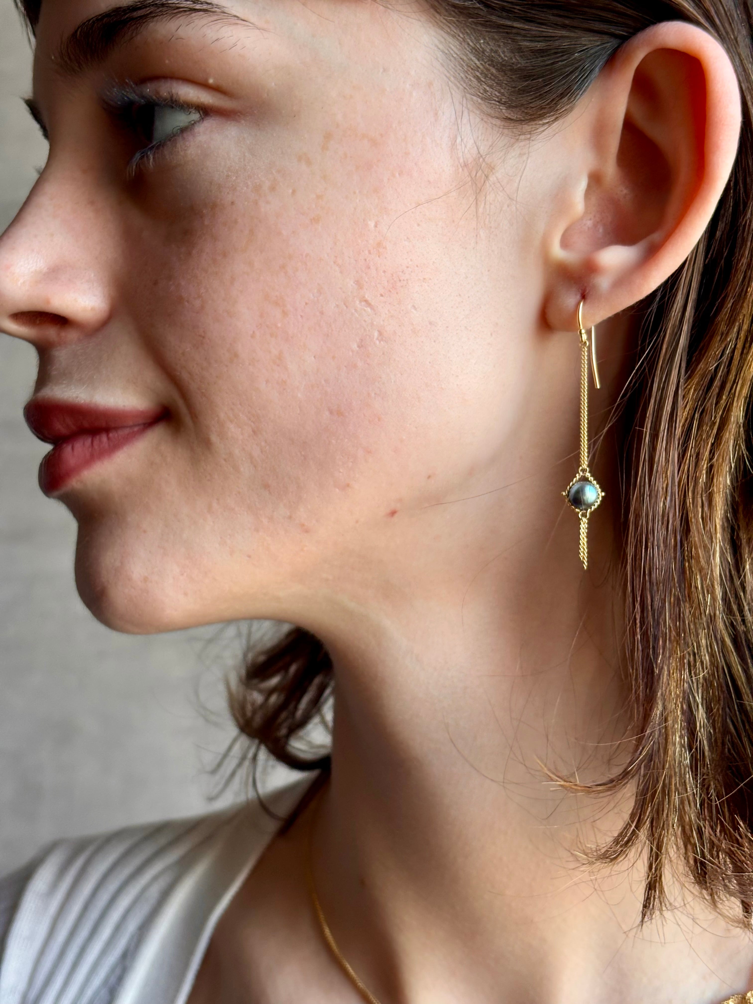 Woman wearing refined fine jewelry with iridescent blue Akoya pearls in an elegantly wearable drop silhouette in 18k yellow gold from New york designer Amali with kinetic  fun fringe bottom detail