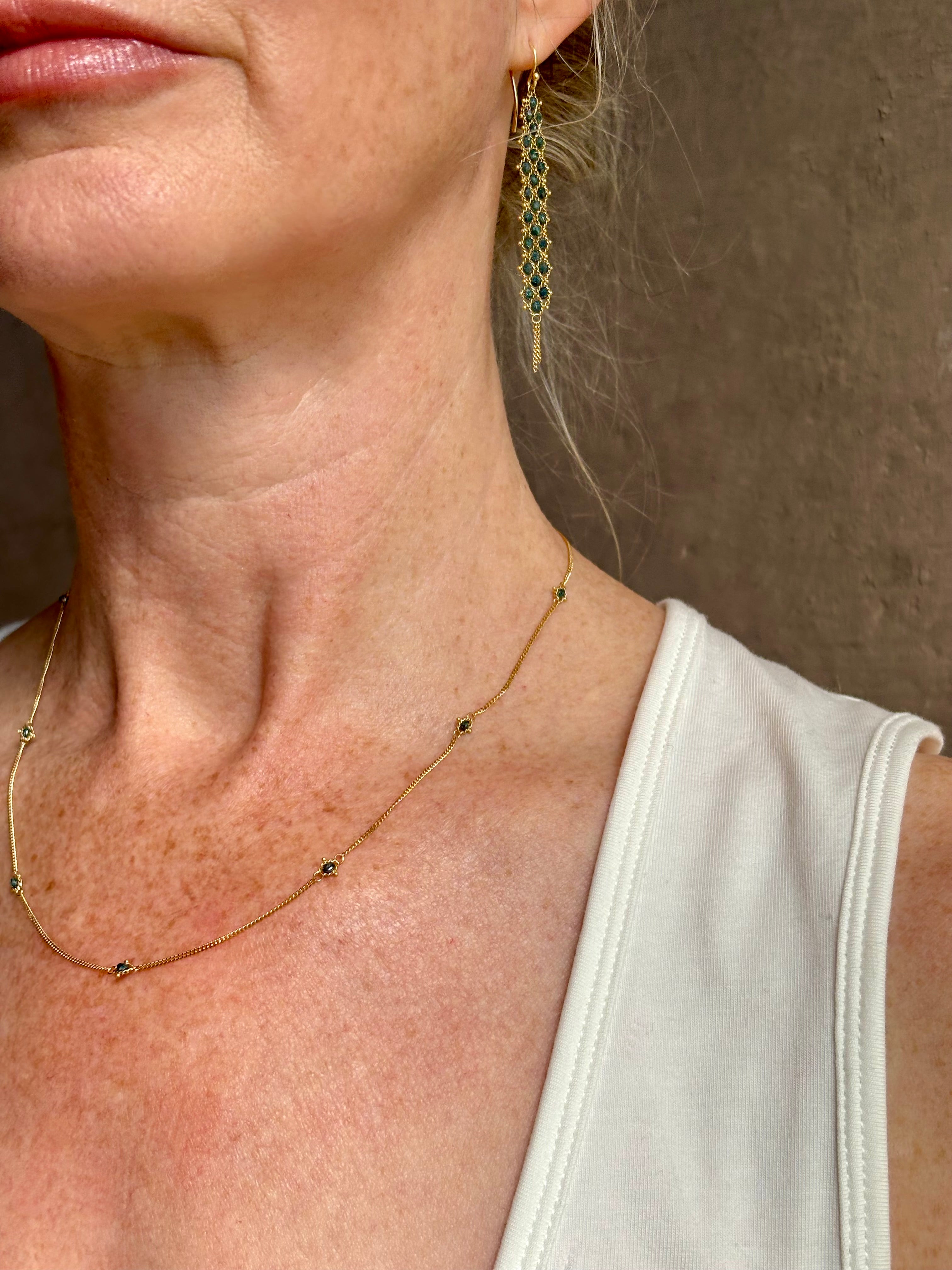 Mature woman wearing a natural blue diamond chain necklace handcrafted by  North Carolina fine jewelry designer Amali in warm 18K yellow gold with a refreshing contemporary design