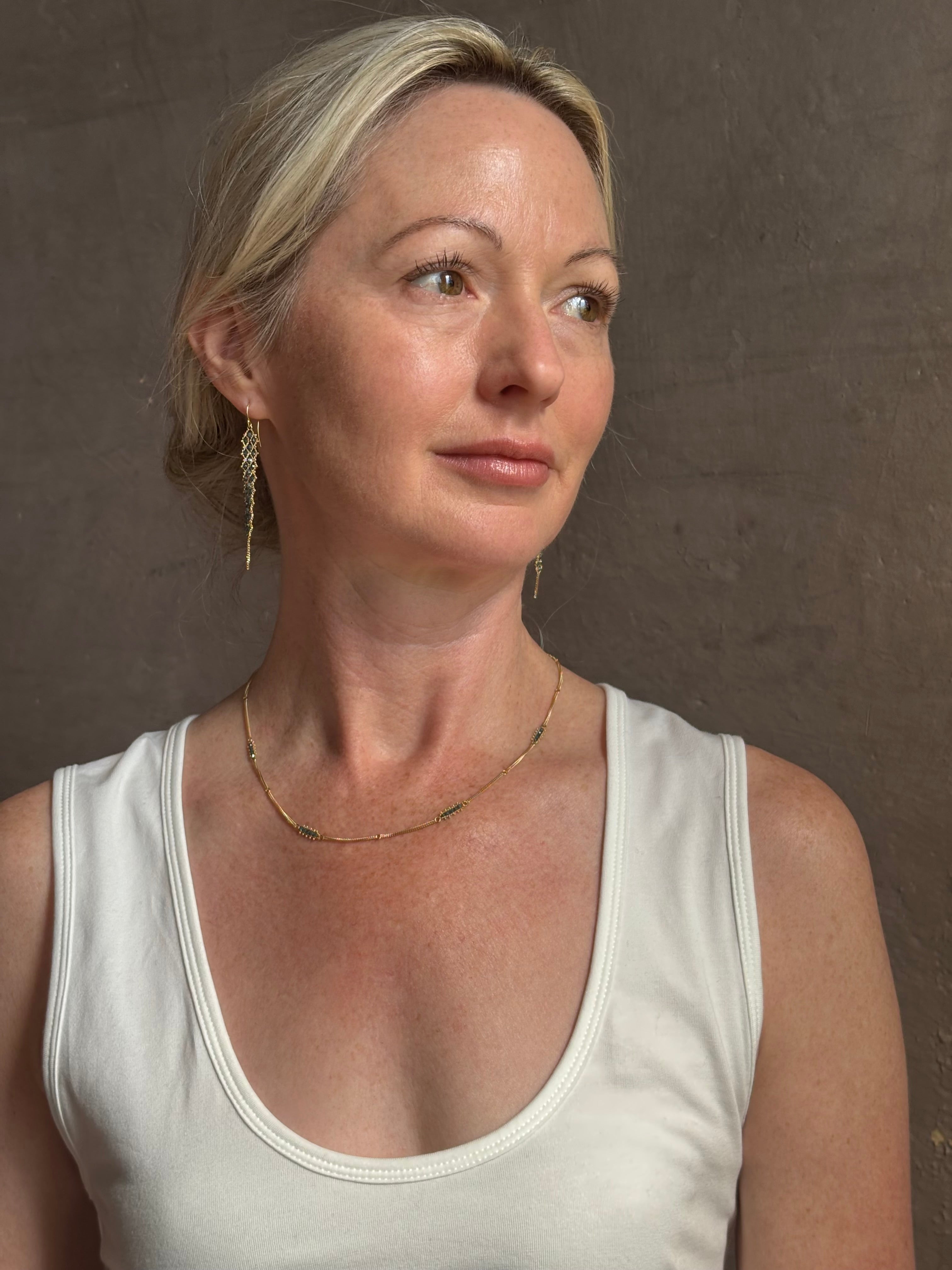 Mature woman wearing a double layered chain natural blue diamond necklace from fine jewelry designer Amali handcrafted in Chapel Hill North Carolina in warm 18K yellow gold