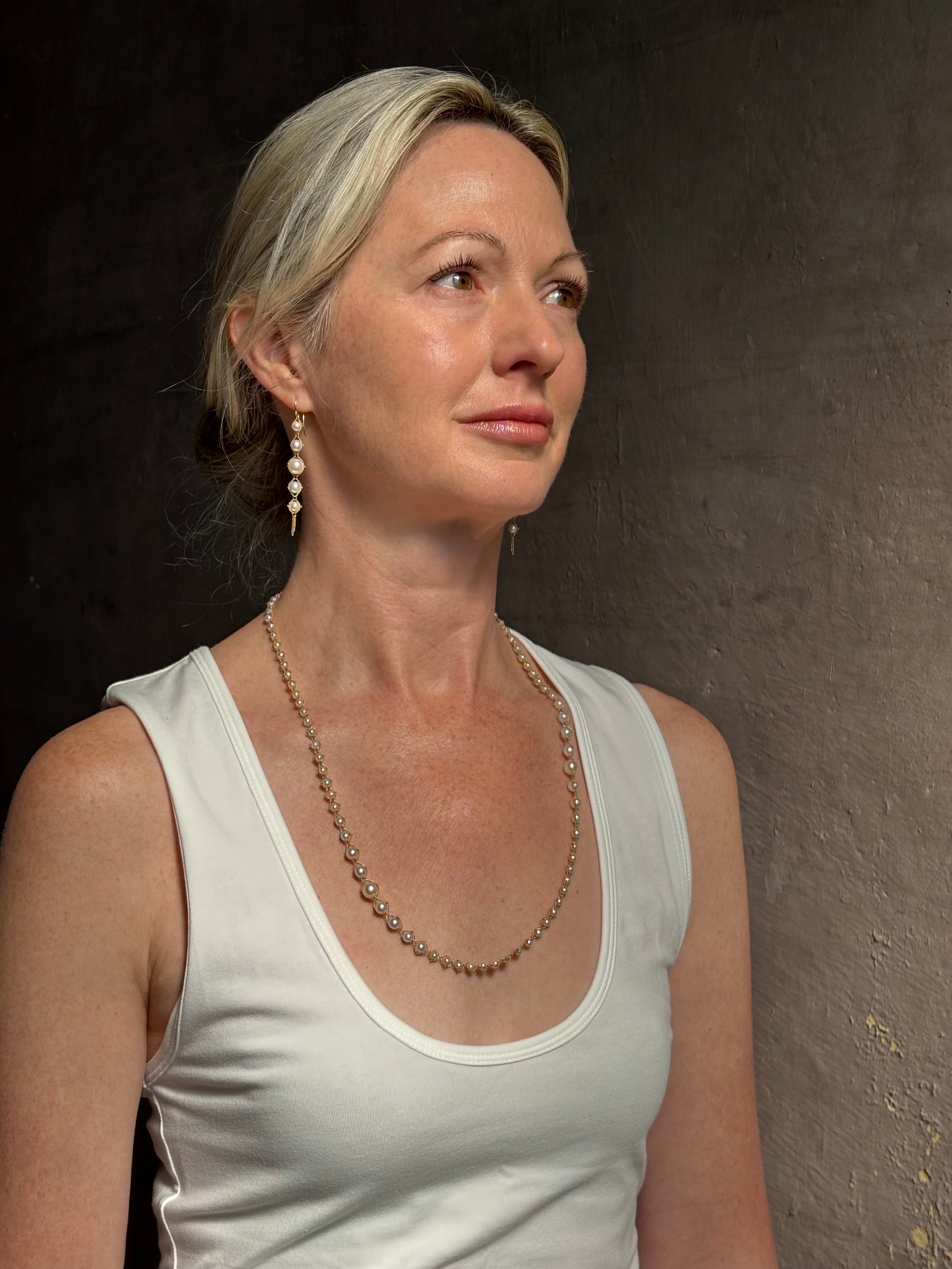 Image of graduated Akoya Pearl Drop Earrings from North Carolina fine jewelry artist Amali with each lustrous white Akoya pearl individually suspended in hand-woven lengths of delicate 18K yellow gold chain and french wire hooks