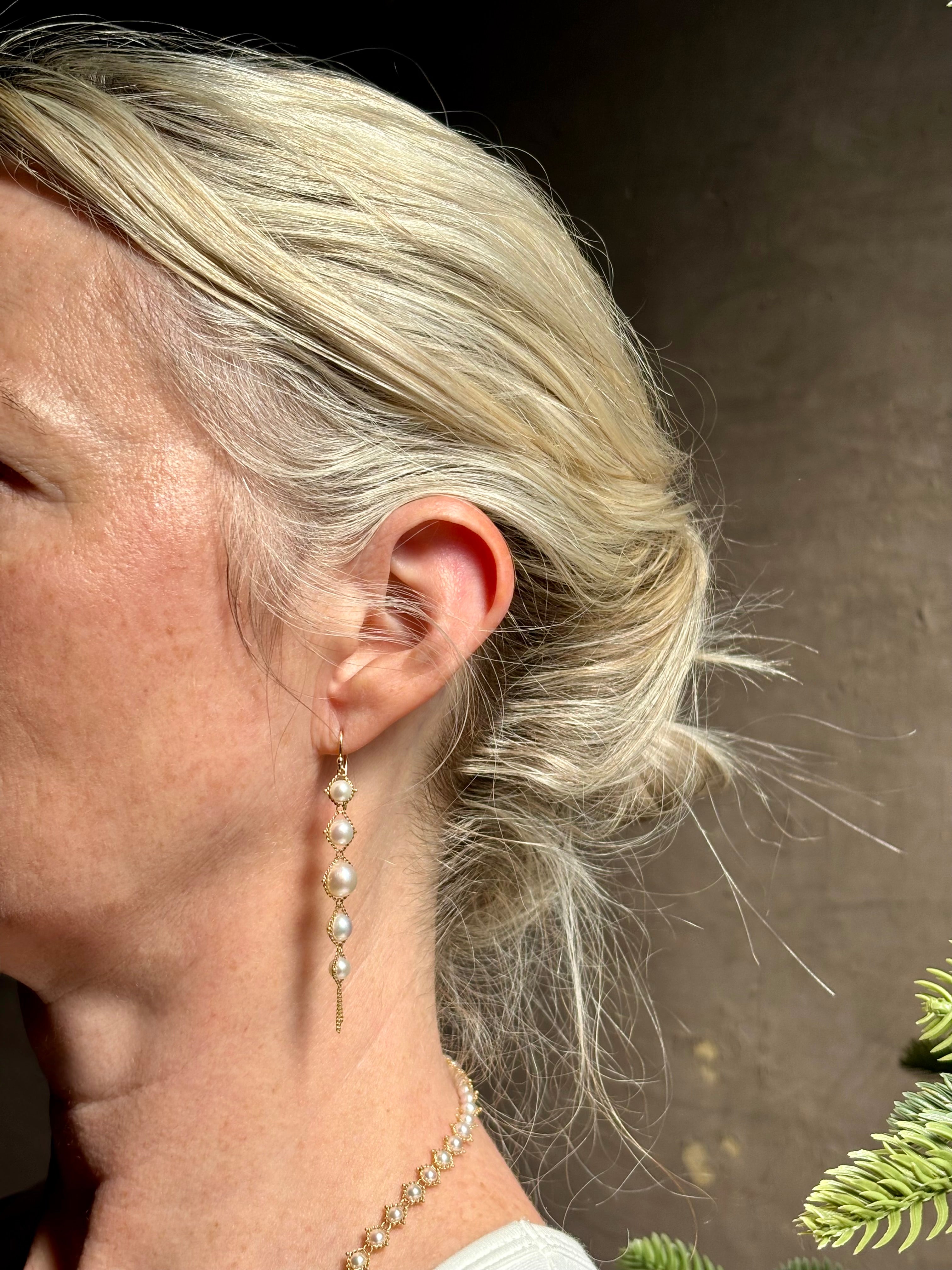 Image of graduated Akoya Pearl Drop Earrings from North Carolina fine jewelry artist Amali with each lustrous white Akoya pearl individually suspended in hand-woven lengths of delicate 18K yellow gold chain and french wire hooks
