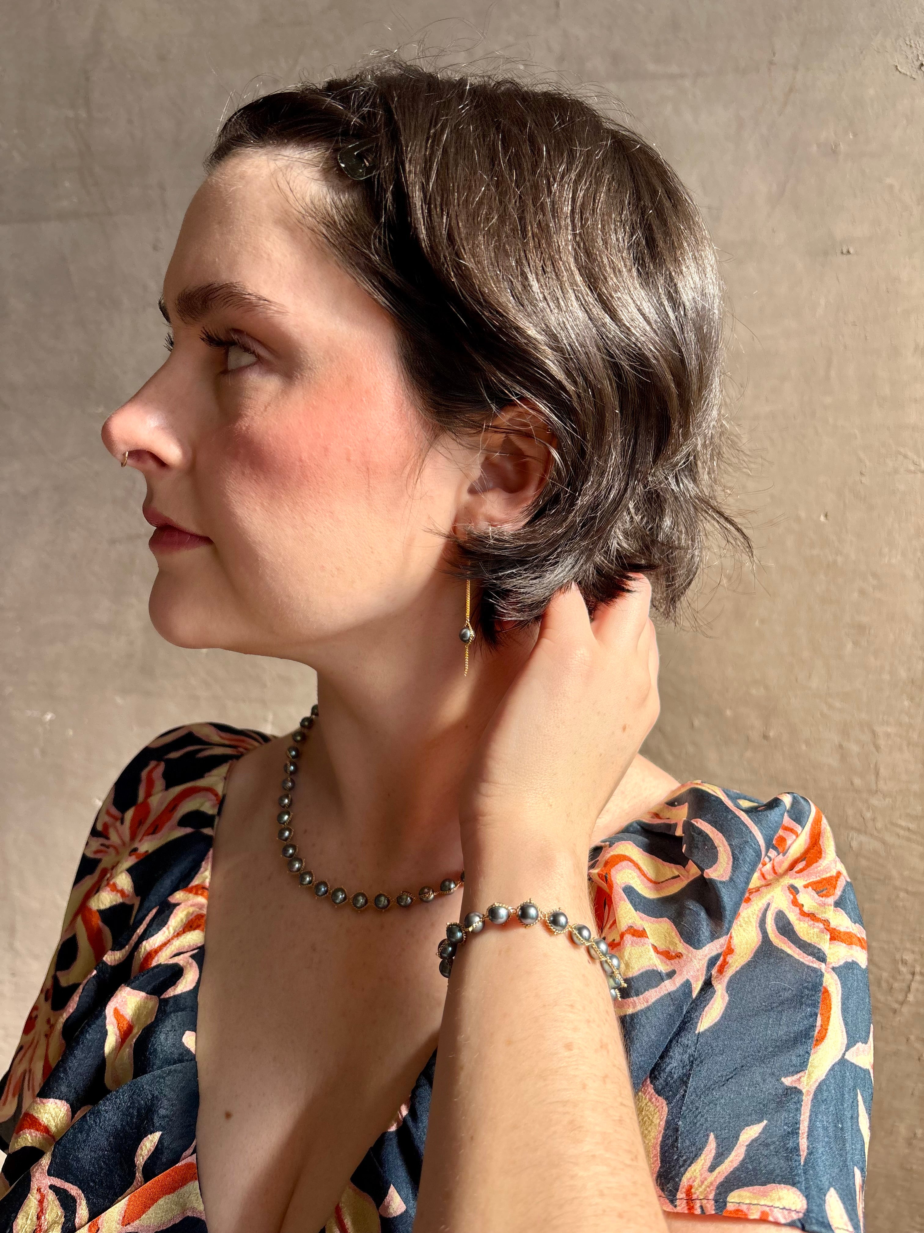 Woman wearing luxury Grey Akoya Pearl Necklace from fine jewelry artist Amali handcrafted in New York in warm 18K yellow gold with matching necklace and earrings