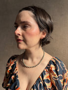 Woman wearing luxury Grey Akoya Pearl Necklace from fine jewelry artist Amali handcrafted in New York in warm 18K yellow gold with matching earrings