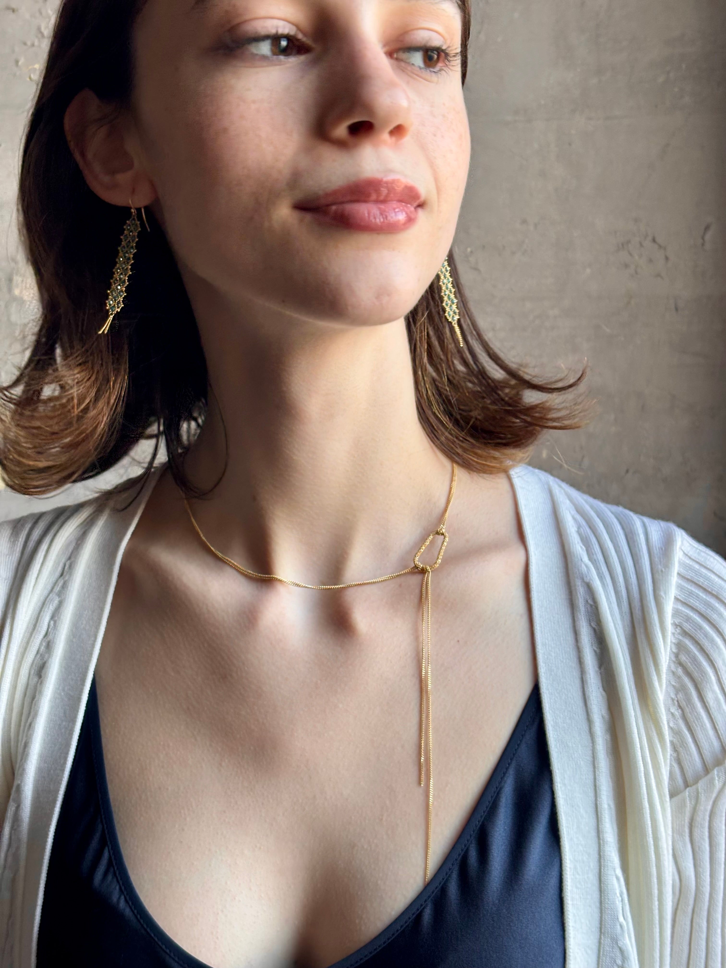 Woman wearing 18k yellow gold stardust Lariat Necklace from fine jewelry artist Amali and handmade in New York. Designed to be worn asymmetrically to the side offering a modern, fashion-forward twist to a classic