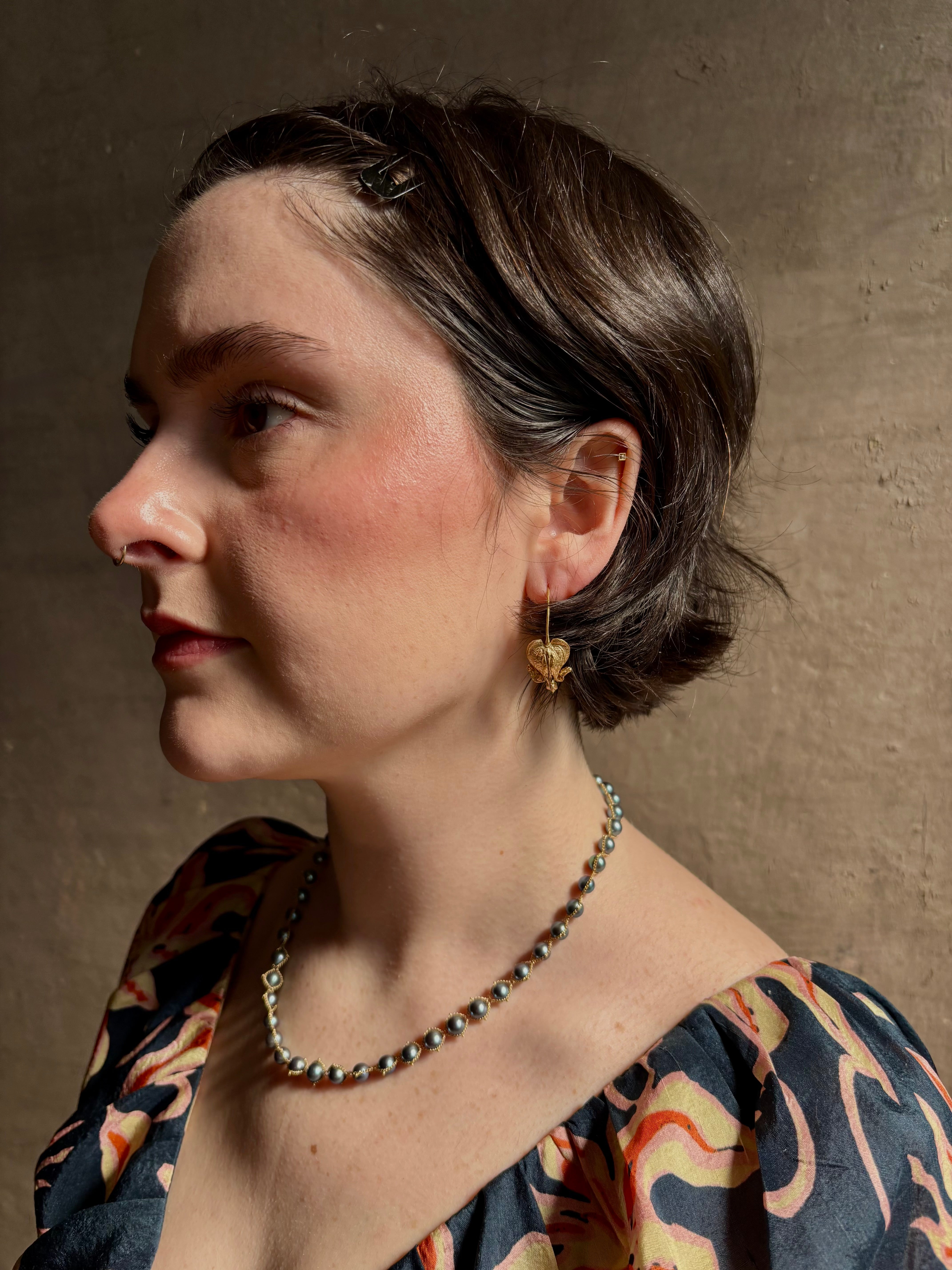 Woman wearing Bleeding Heart Hoop Earrings from North Carolina fine Jewelry artist Amber Mahler handcrafted 18K yellow gold vermeil botanical casting. 