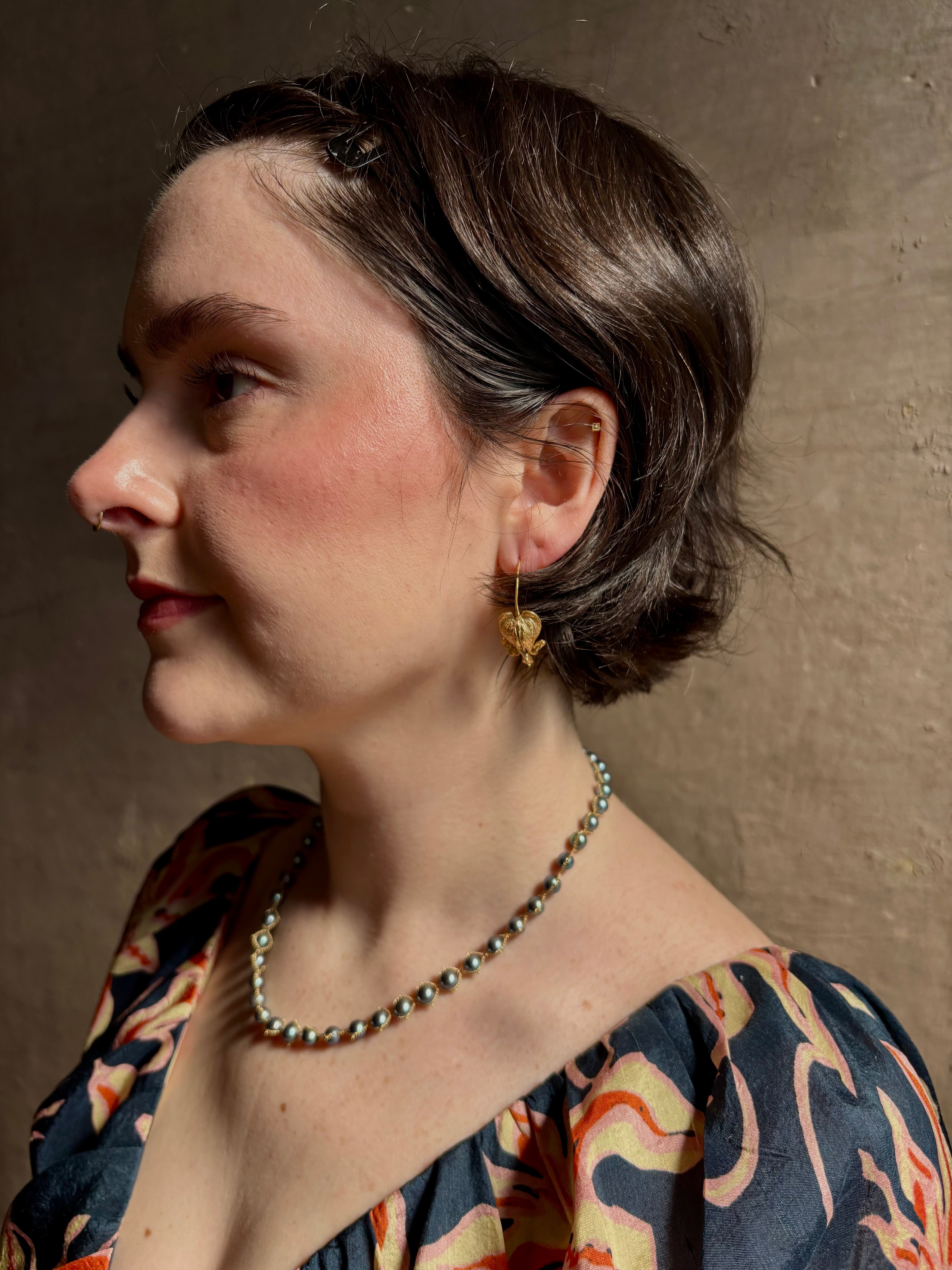 Woman wearing Bleeding Heart Hoop Earrings from North Carolina fine Jewelry artist Amber Mahler handcrafted 18K yellow gold vermeil botanical casting. 