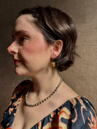 Woman wearing Bleeding Heart Hoop Earrings from North Carolina fine Jewelry artist Amber Mahler handcrafted 18K yellow gold vermeil botanical casting. 