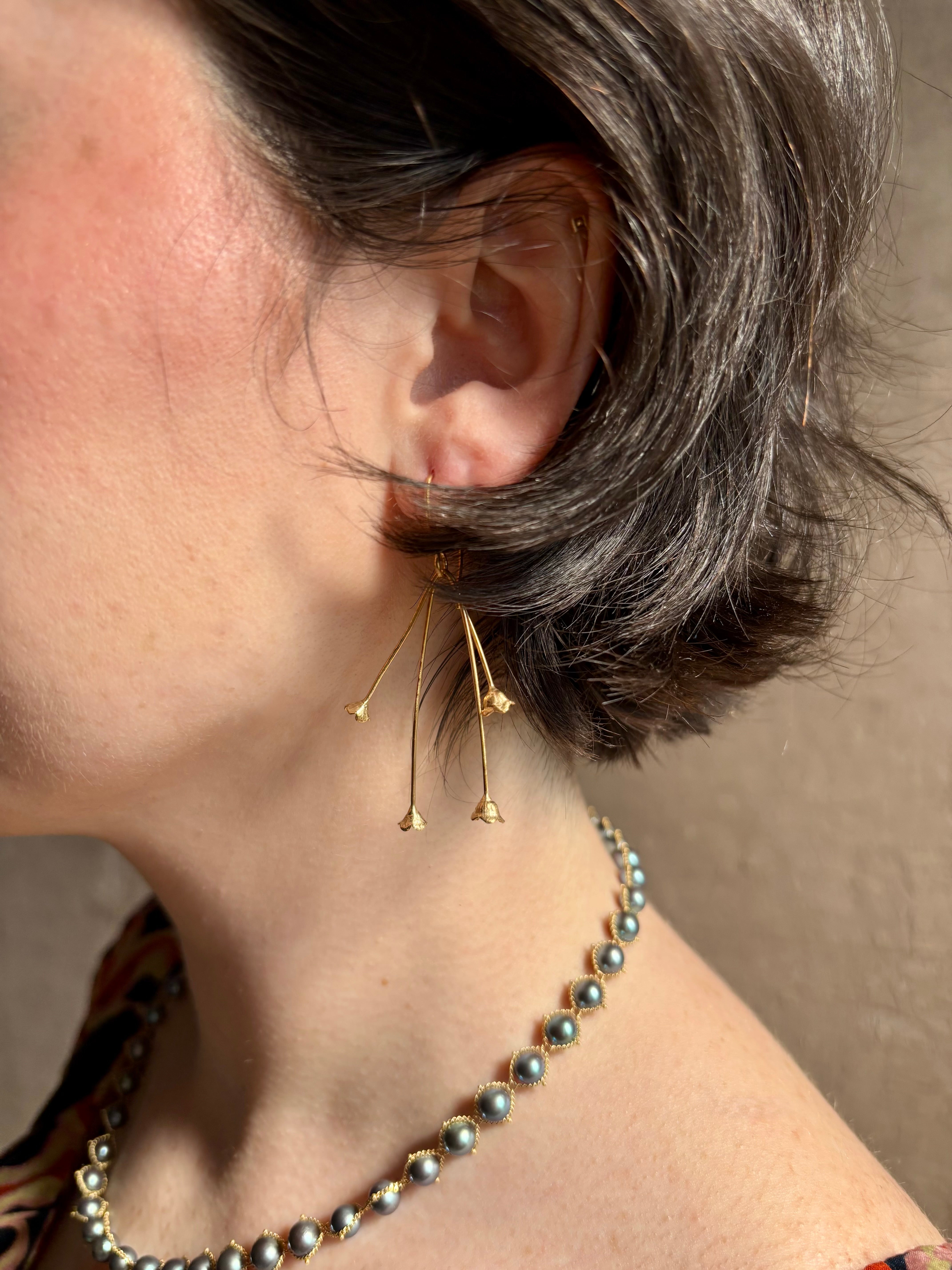 Woman wearing Lily of the Valley Earrings from North Carolna fine jewelry artist Amber Mahler handcrafted 18K yellow gold vermeil with four dangling flower blossoms