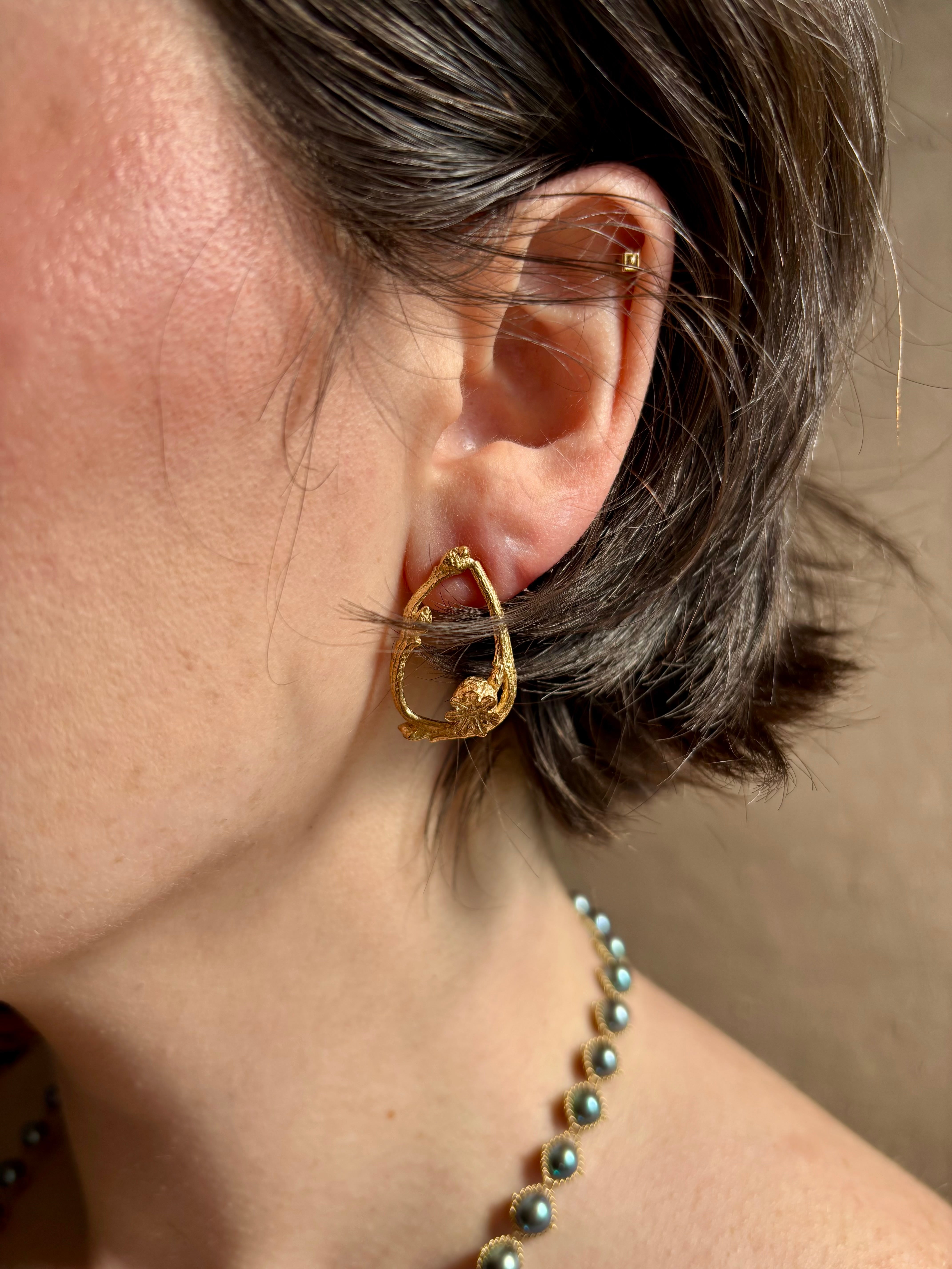 Woman wearing Poppy Pod and Blueberry Branch post Earrings from North Carolina fine jewelry artist Amber Mahler handcrafted 18K yellow gold vermeil casting. 