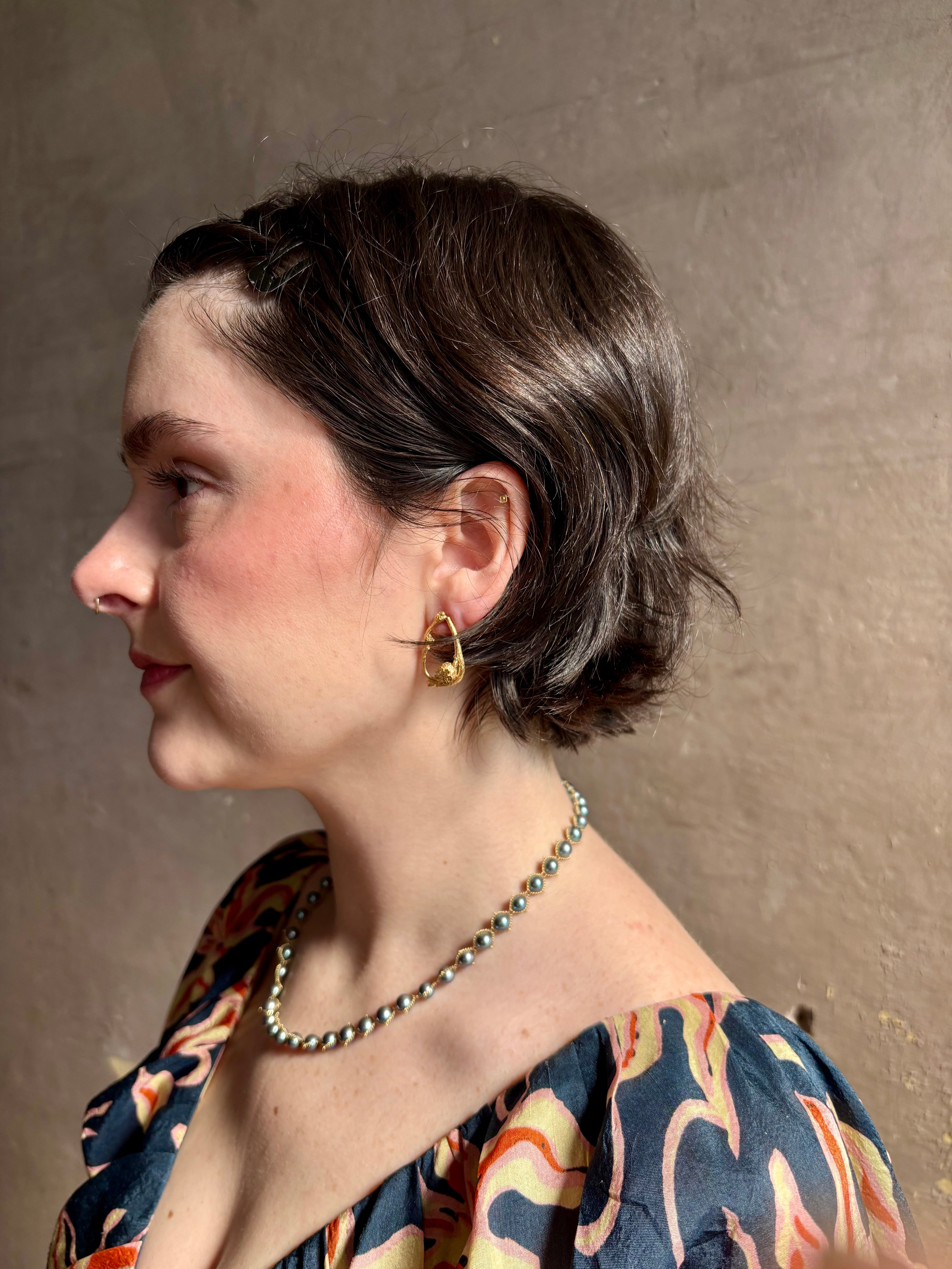 Woman wearing Poppy Pod and Blueberry Branch post Earrings from North Carolina fine jewelry artist Amber Mahler handcrafted 18K yellow gold vermeil casting. 