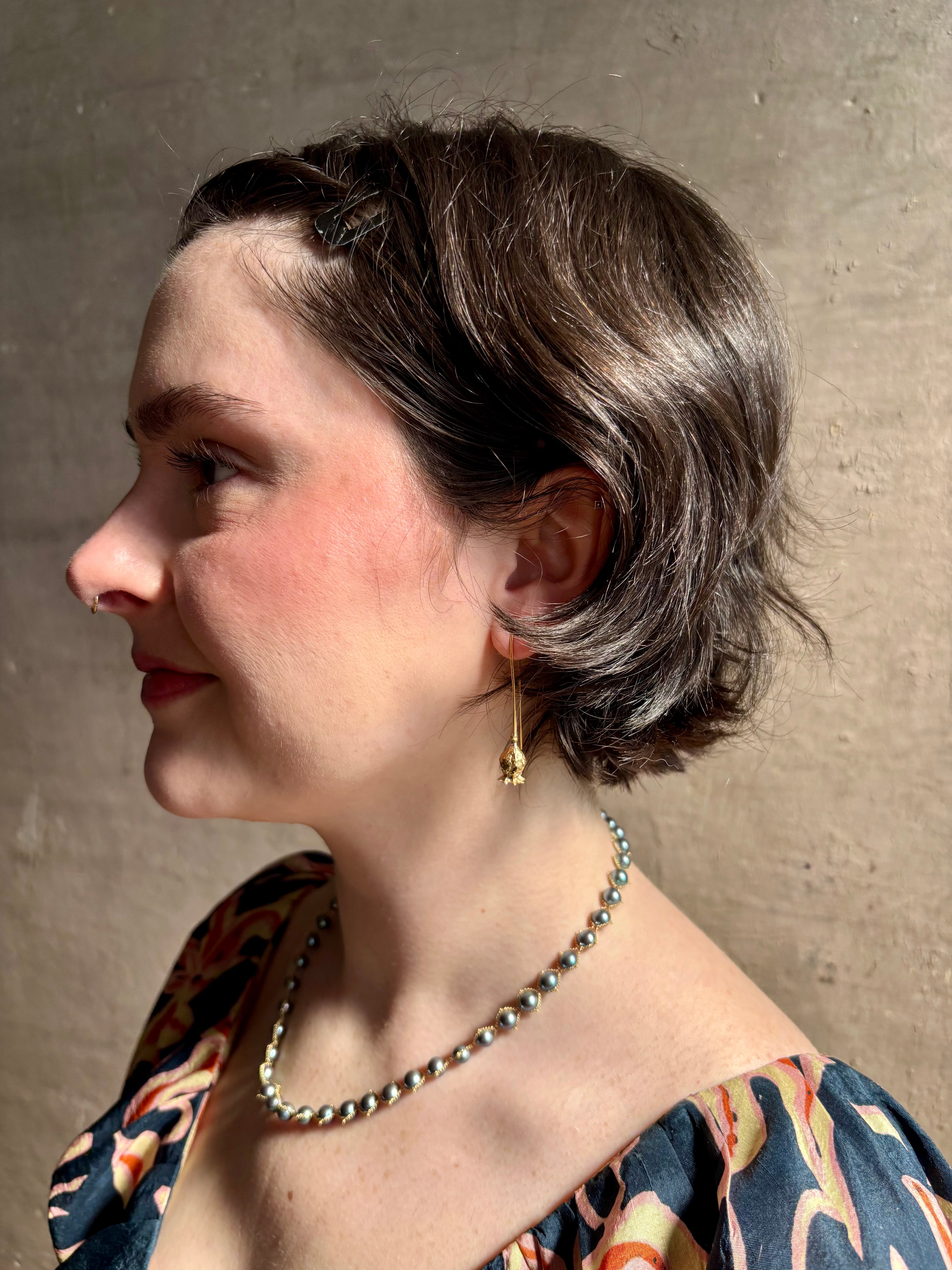 Woman wearing Poppy Pod Drop Earrings from North Carolina fine jewelry artist Amber Mahler handcrafted 18K yellow gold vermeil botanical casting