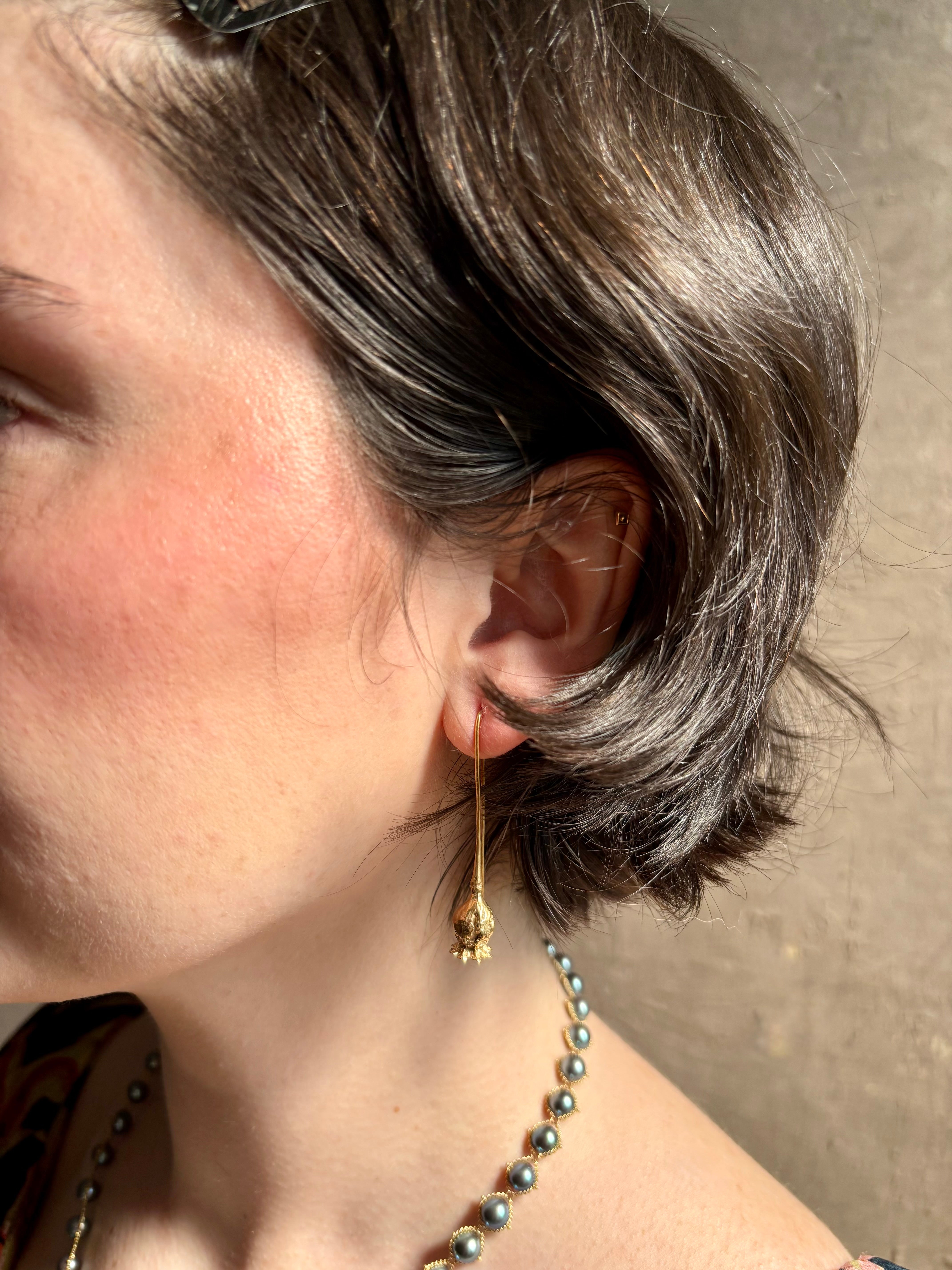 Woman wearing Poppy Pod Drop Earrings from North Carolina fine jewelry artist Amber Mahler handcrafted 18K yellow gold vermeil botanical casting
