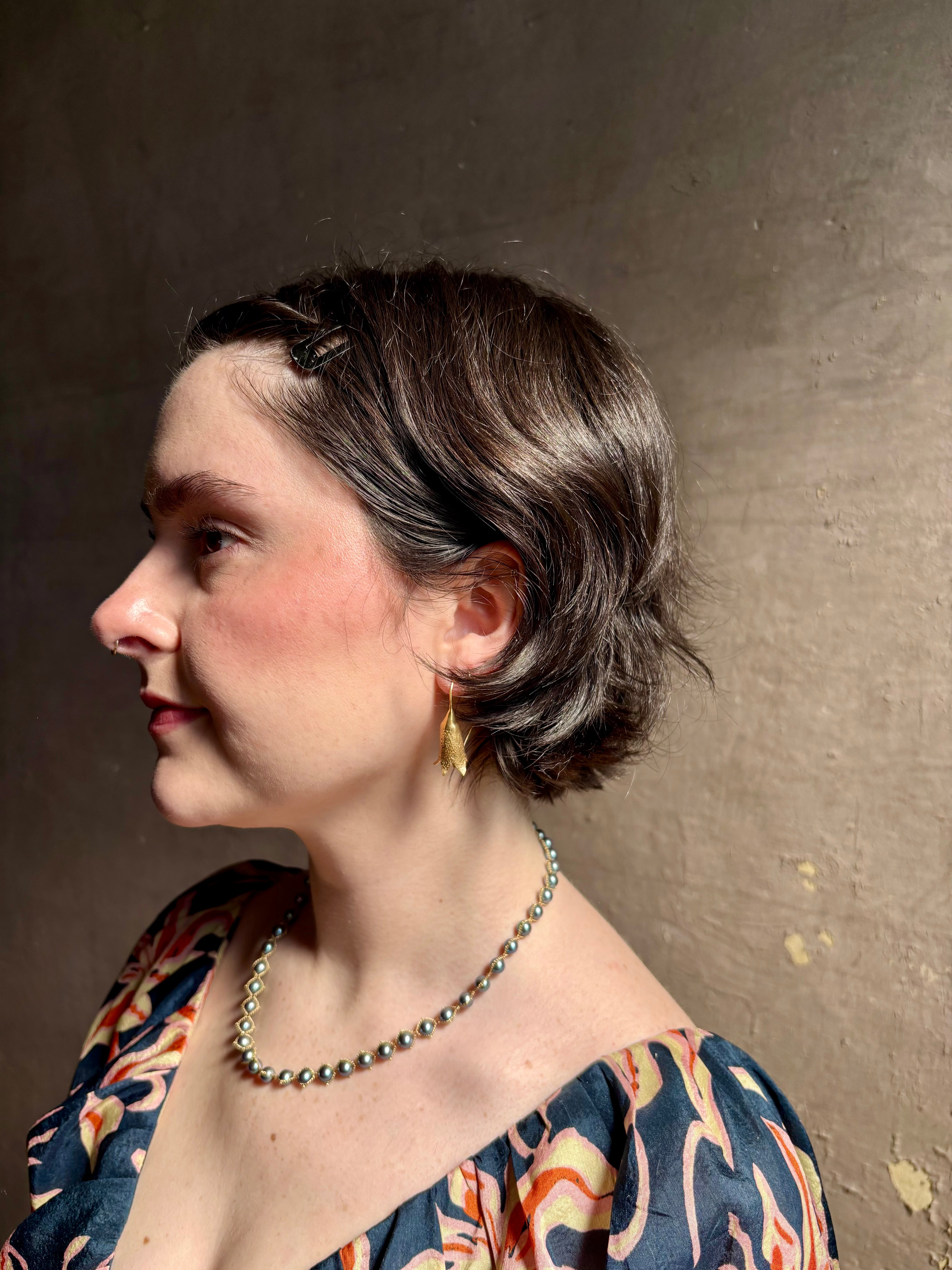 Woman wearing Silver Bells Hoop Earrings from North Carolina fine jewelry artist Amber Mahler in an exquisitely handcrafted 18K yellow gold vermeil botanical casting