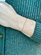 Image of a woman wearing designer Anne Sportun 18 carat gold diamond stardust bracelet single bar with hammered texture and adjustable clasp