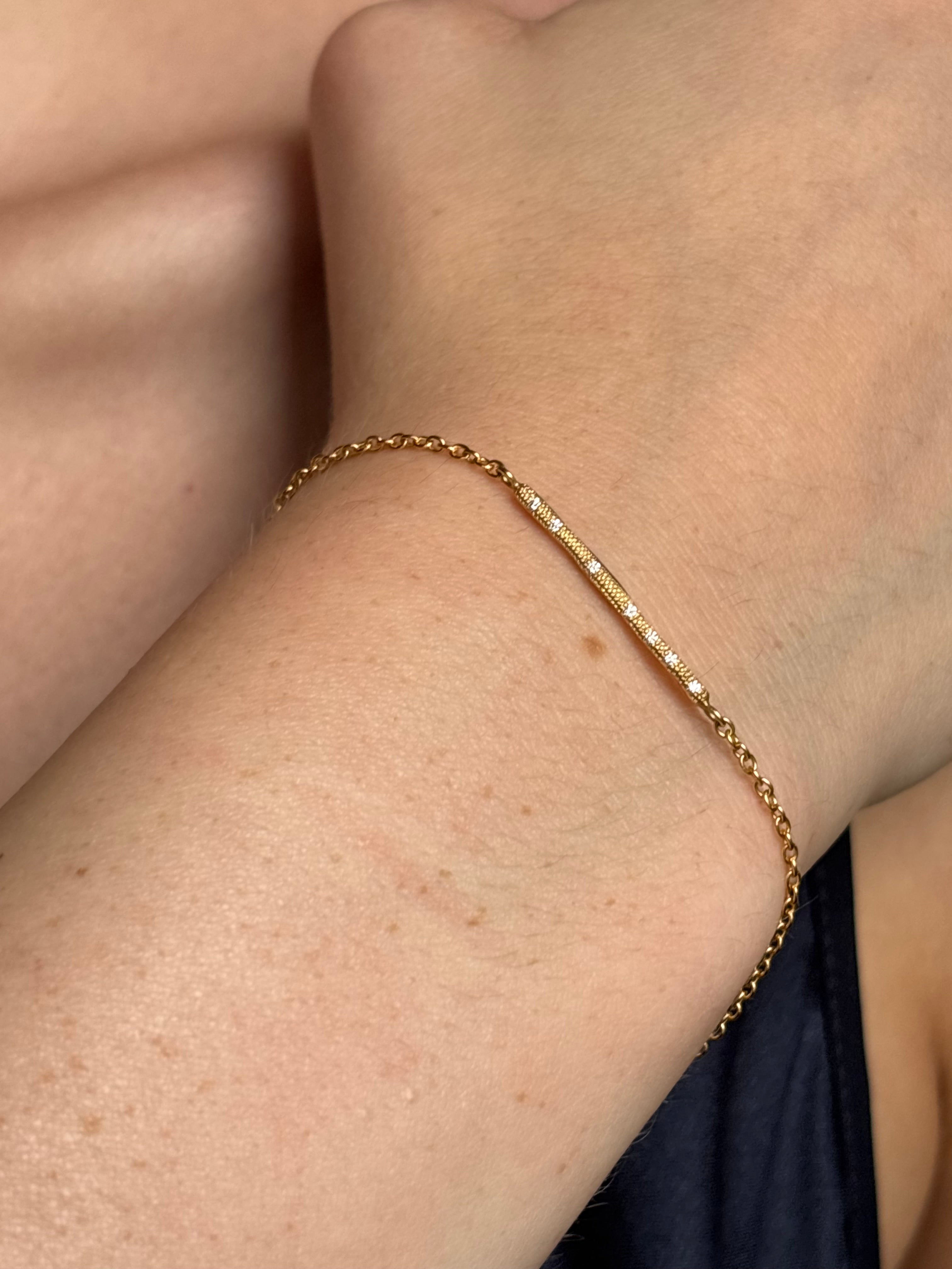 woman wearing designer Anne Sportun 18 carat gold diamond stardust bracelet single bar with hammered texture and adjustable clasp