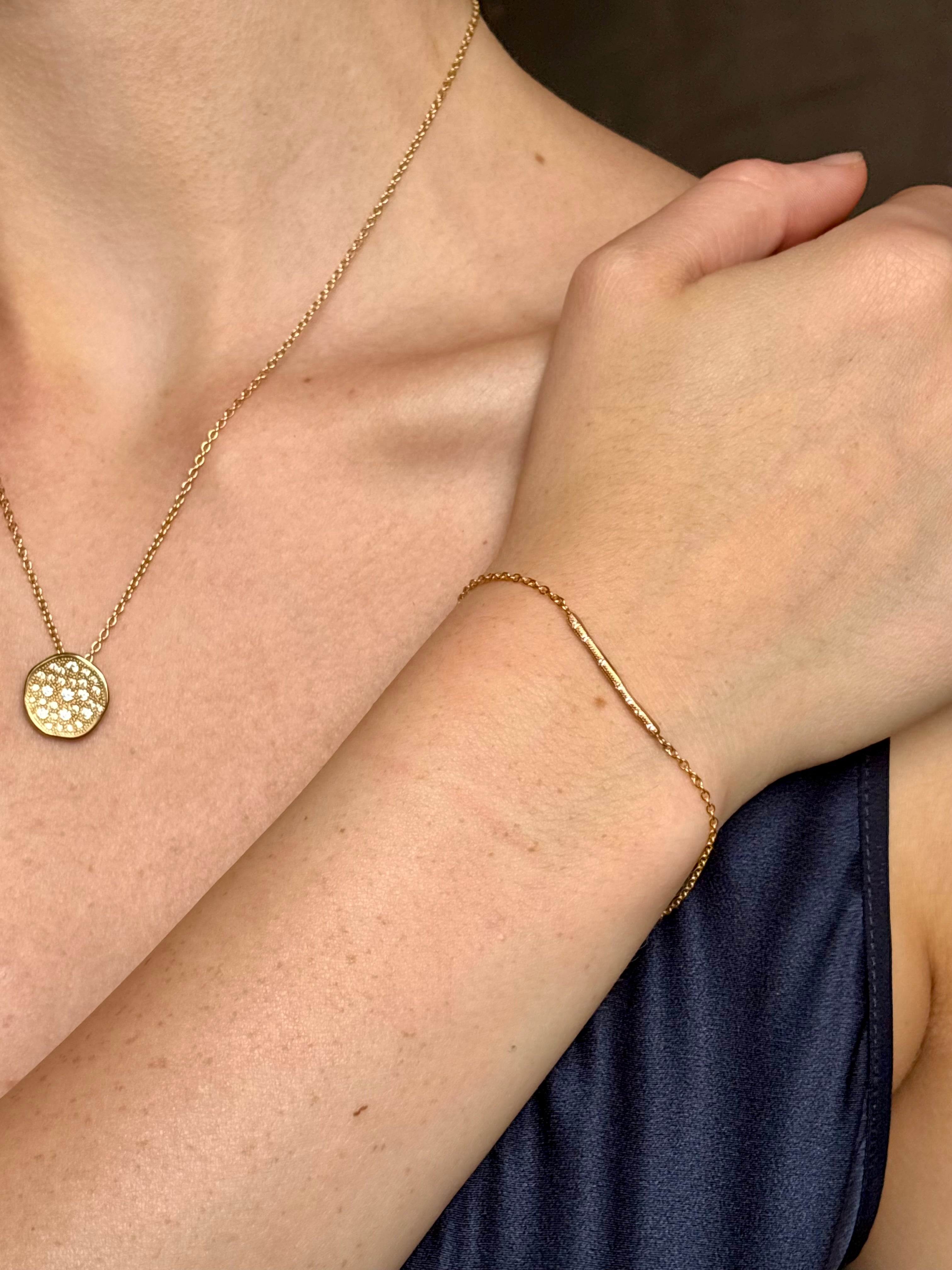 woman wearing designer Anne Sportun 18 carat gold diamond stardust bracelet single bar with hammered texture and adjustable clasp