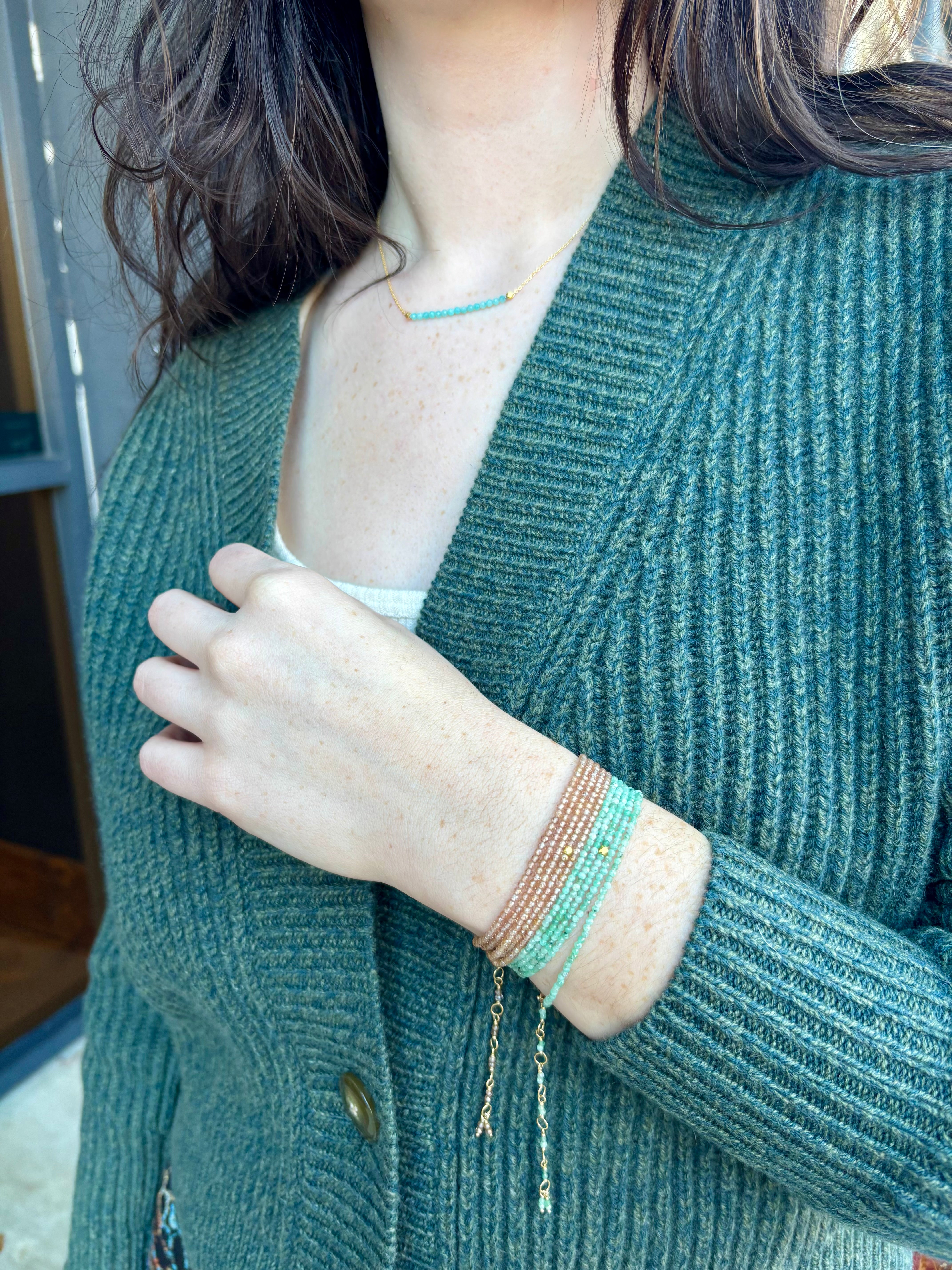 Image of woman wearing Canadian fine jewelry designer ANNE SPORTUN Emerald Wrap Bracelet in 18K Yellow Gold can also be worn as a necklace