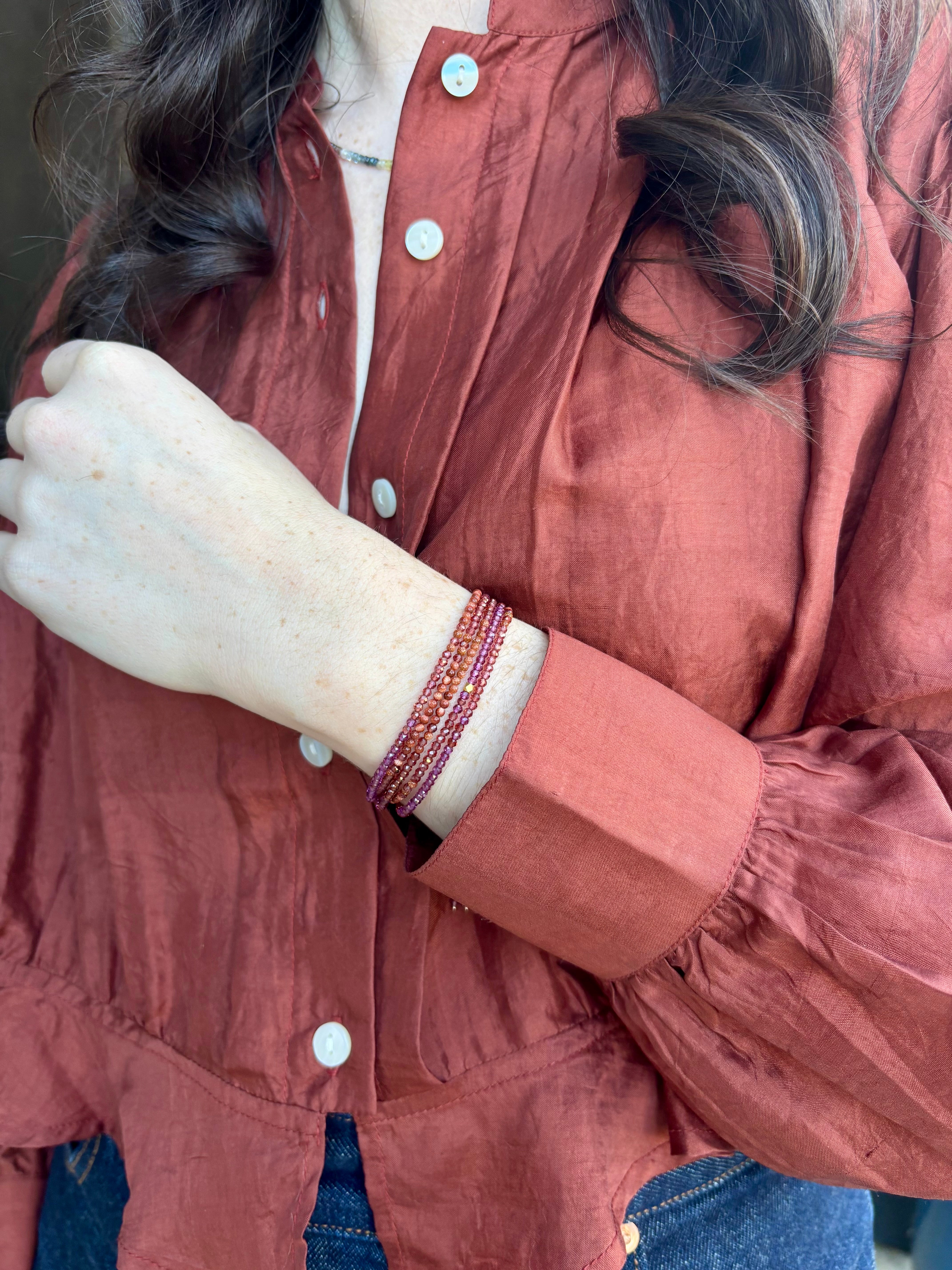 Image of woman wearing designer Anne Sportun ombre wine garnet wrap bracelet with 18 carat yellow gold hardware 