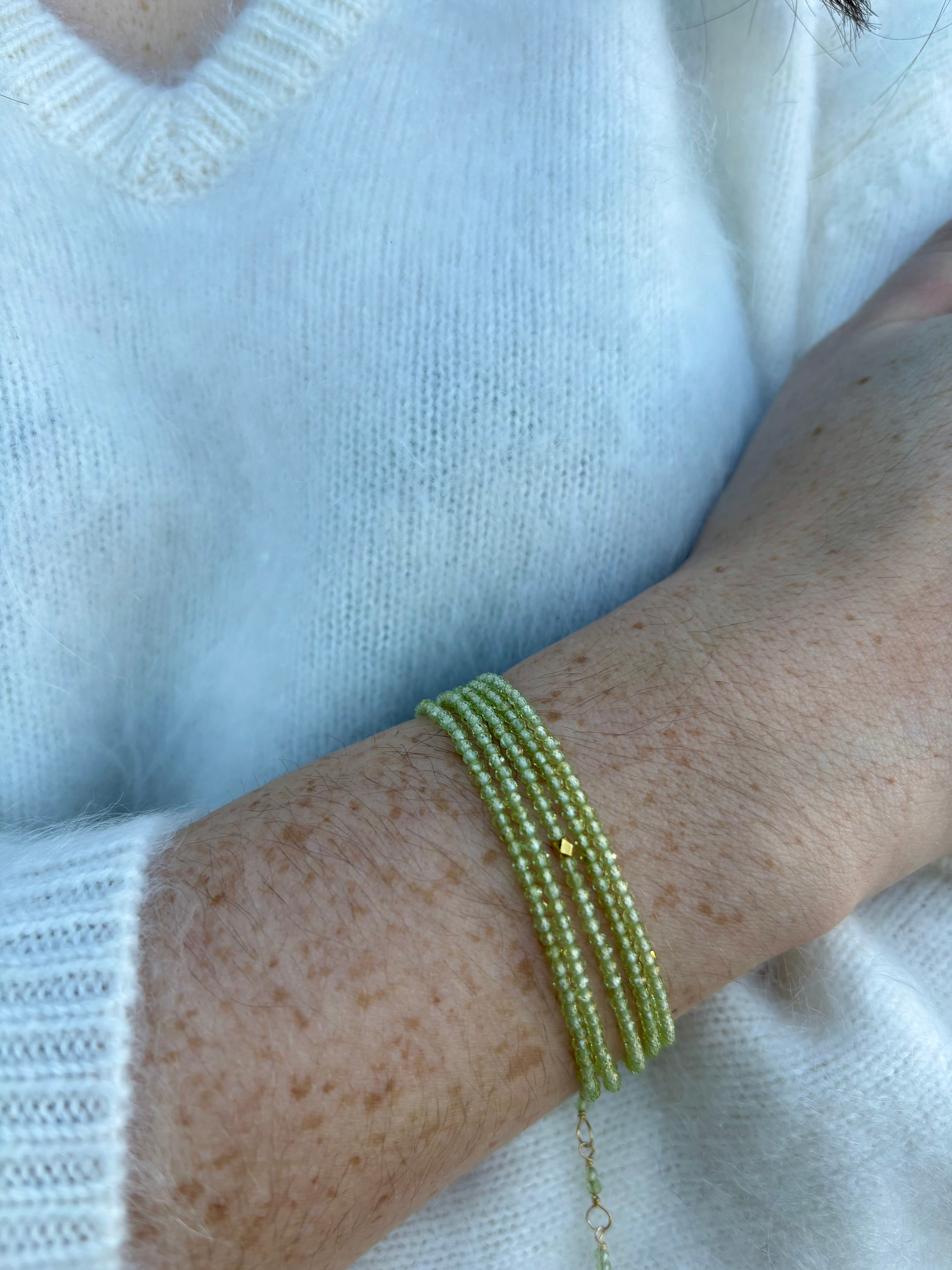 Image of a woman wearing premium peridot and gold bracelet that can also be worn as a necklace by Canadian designer Anne Sportun