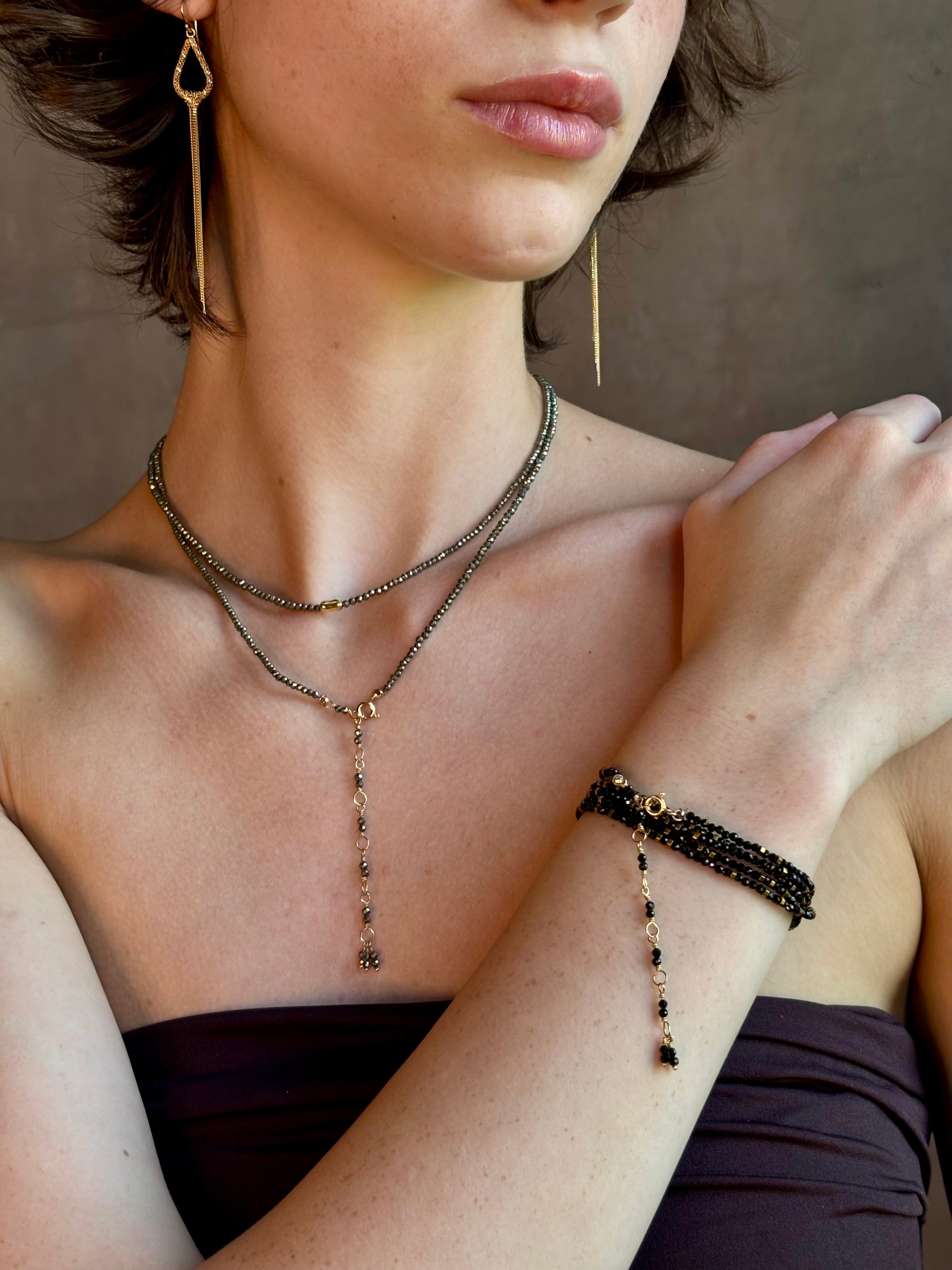 Woman wearing Pyrite River wrap Bracelet from Canadian fine jewelry artist Anne Sportun with pyrite and 18k yellow gold beads that can double as a necklace perfect for travel