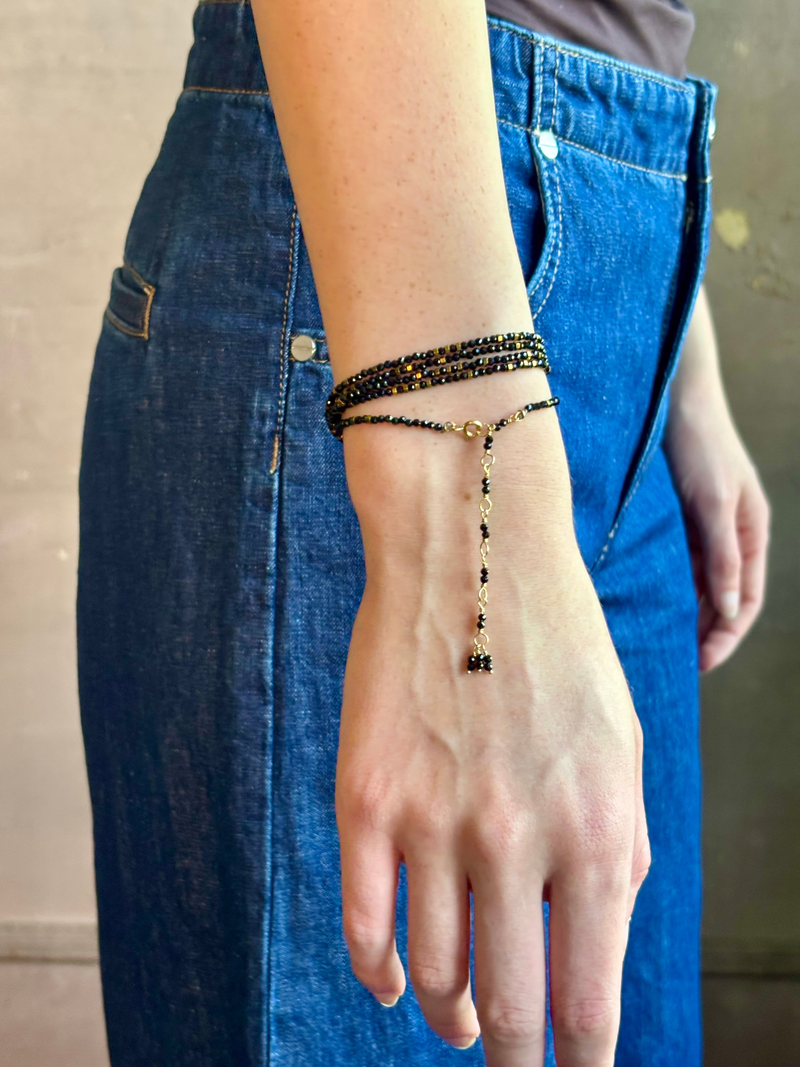 Woman wearing spinel confetti wrap Bracelet from Canadian fine jewelry artist Anne Sportun with natural stone spinel and 18k yellow gold beads that can double as a necklace perfect for travel