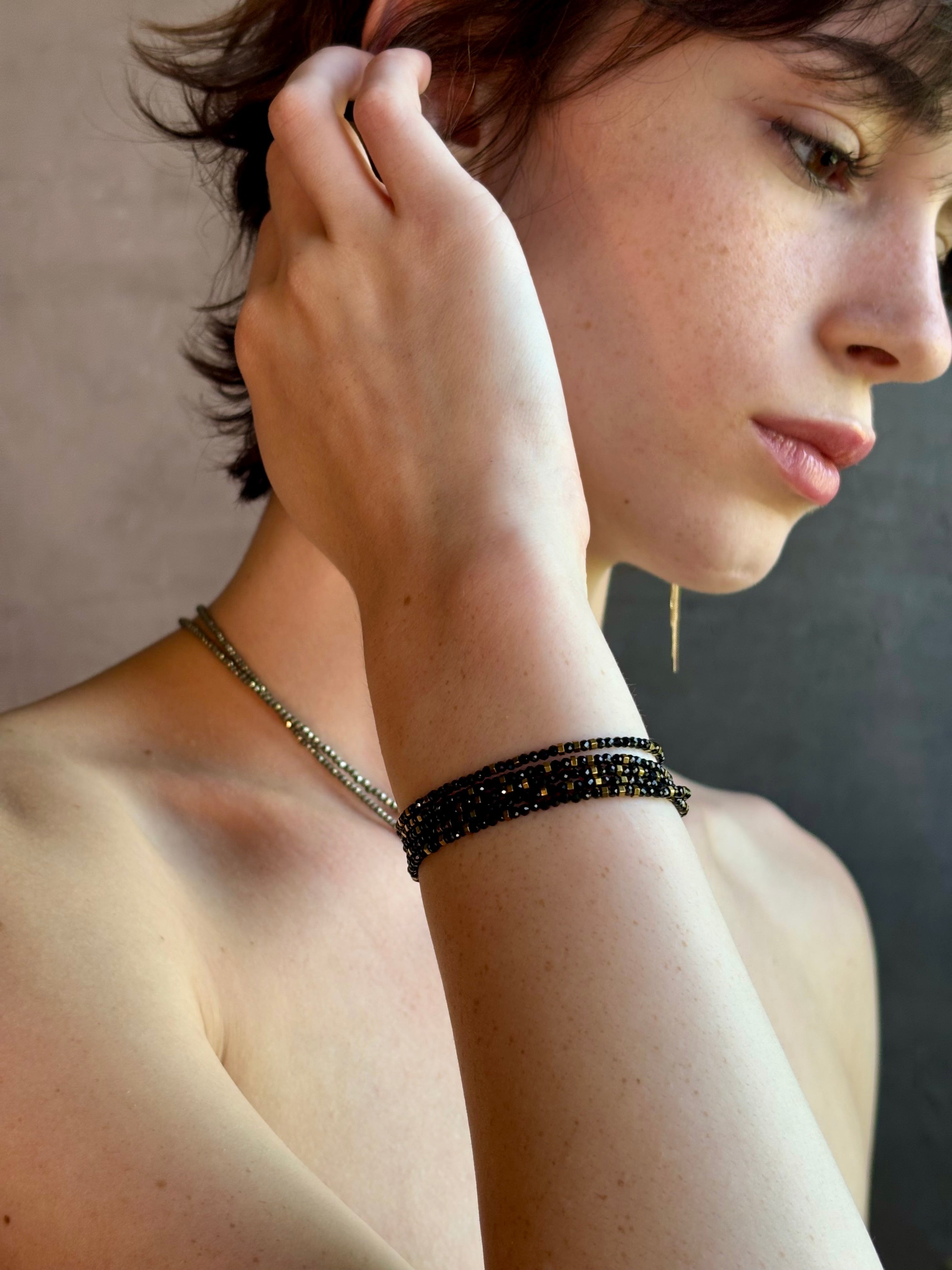 Woman wearing spinel confetti wrap Bracelet from Canadian fine jewelry artist Anne Sportun with natural stone spinel and 18k yellow gold beads that can double as a necklace perfect for travel